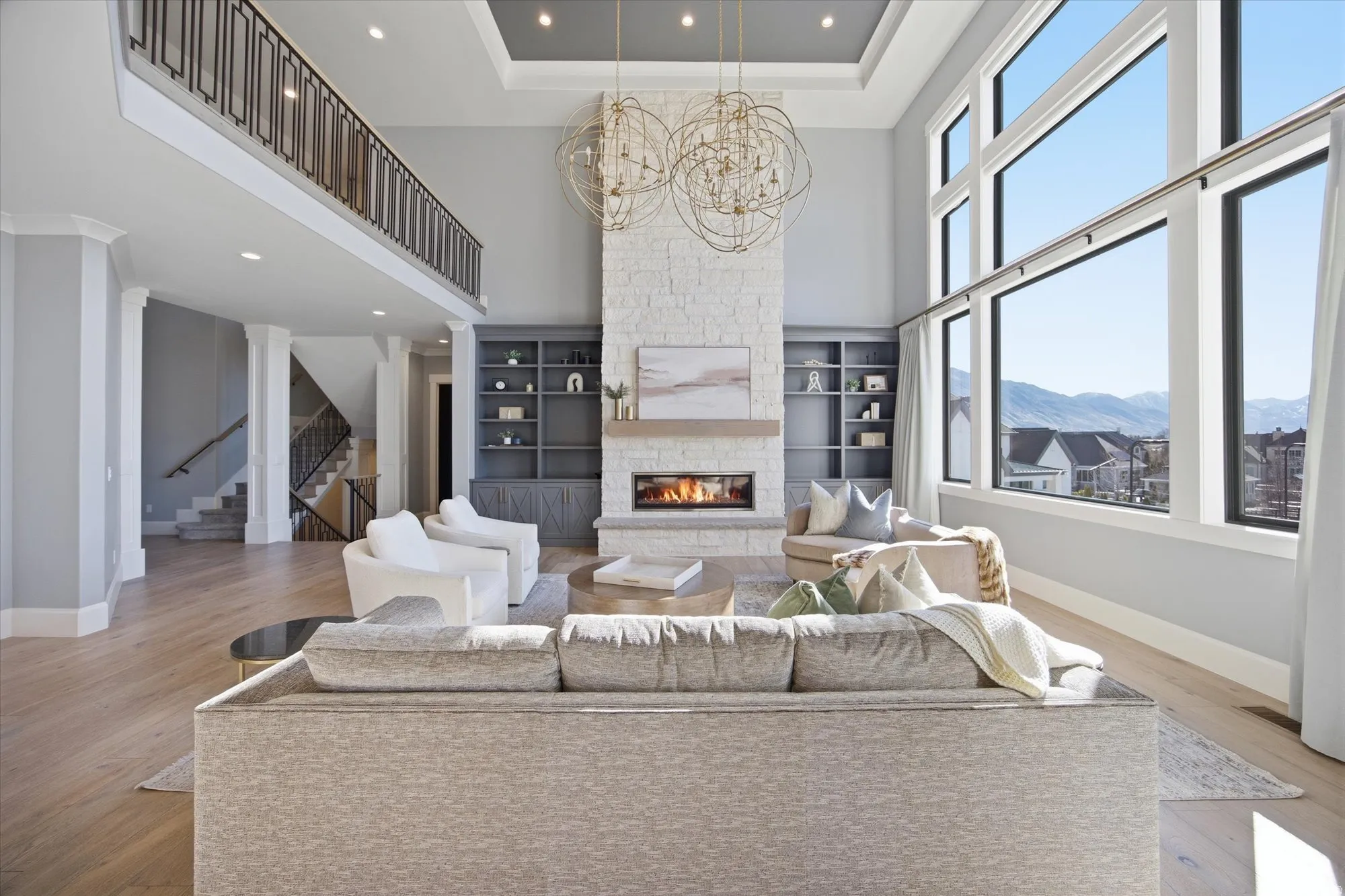 Living area featuring a high ceiling, a chandelier, a fireplace, built in features, and light wood-type flooring
