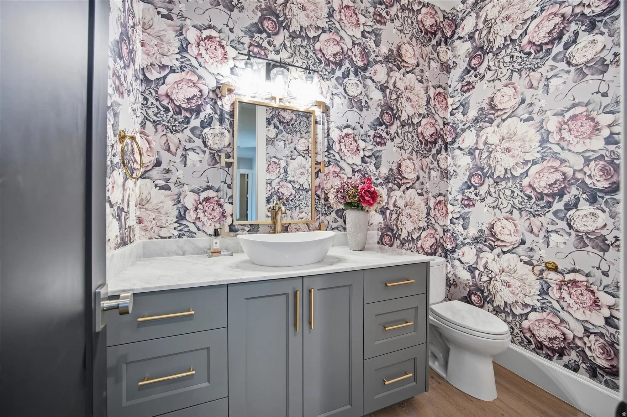 Bathroom with vanity, wallpapered walls, and wood finished floors
