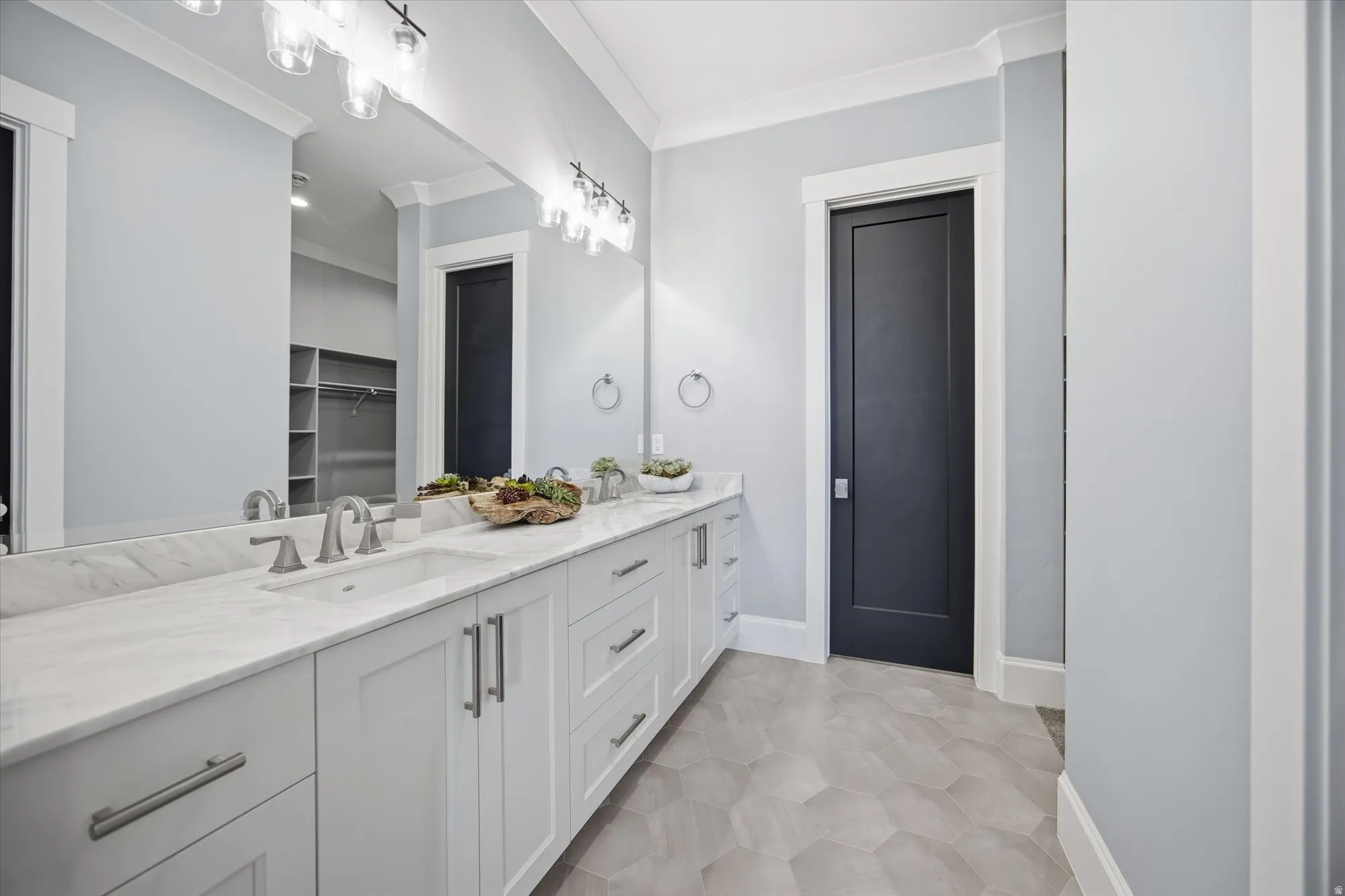 Bathroom featuring double vanity, crown molding, and a walk in closet