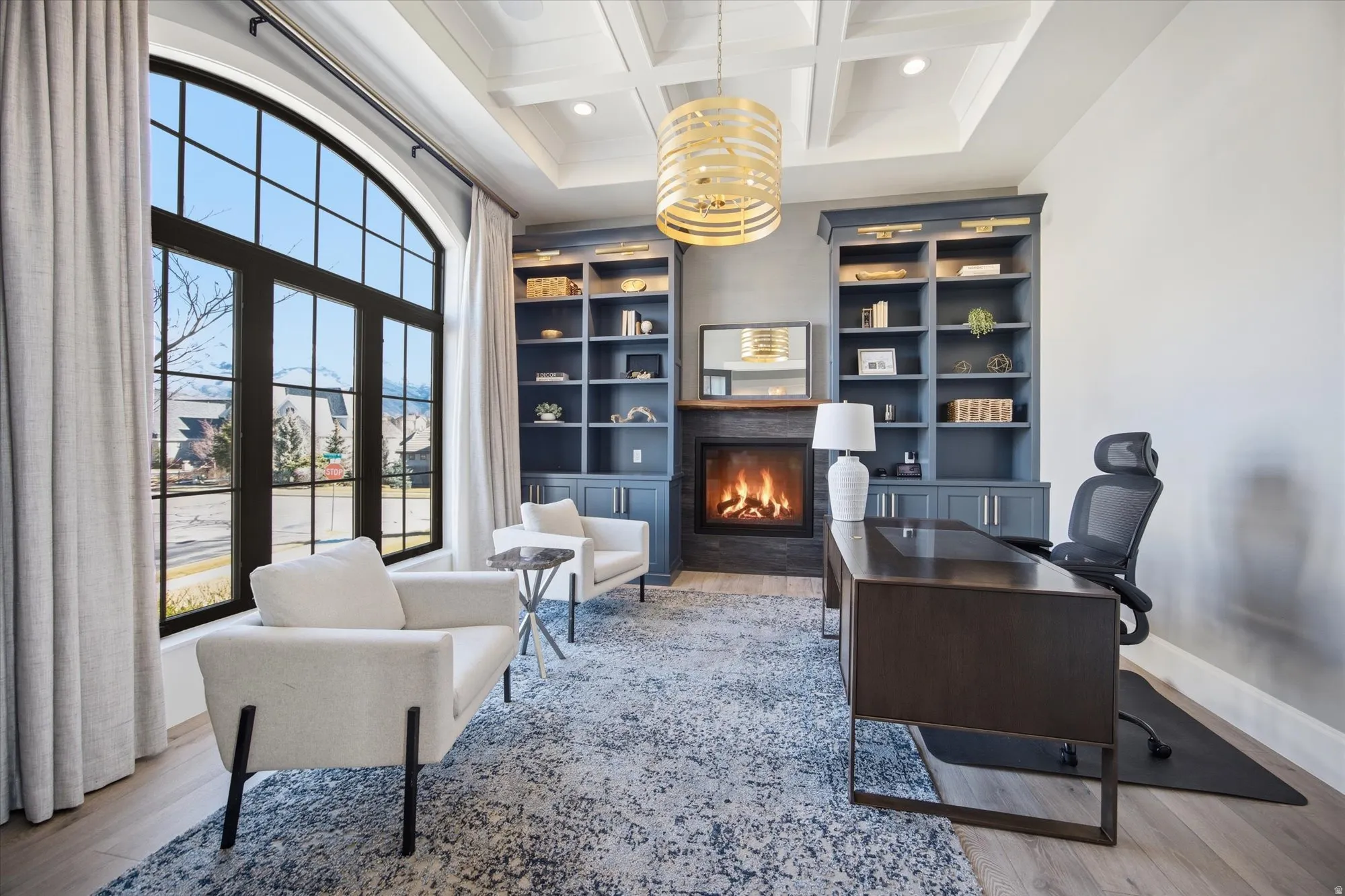 Home office featuring a fireplace with flush hearth, coffered ceiling, built in features, light wood-style floors, and recessed lighting