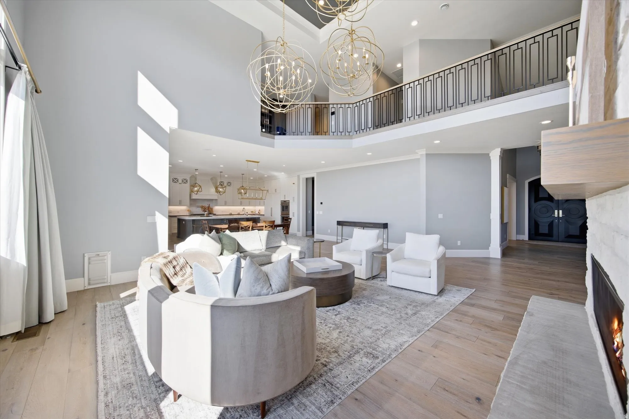 Living room with a warm lit fireplace, light wood-style floors, and a chandelier