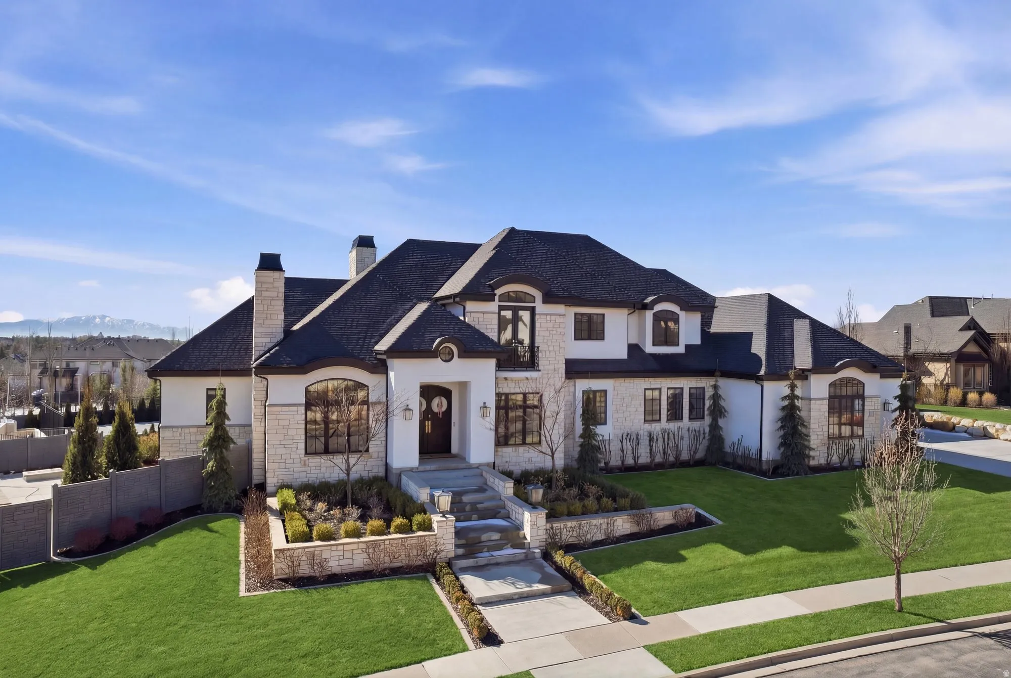 French country style house with stone siding, a chimney, stucco siding, and a mountain view
