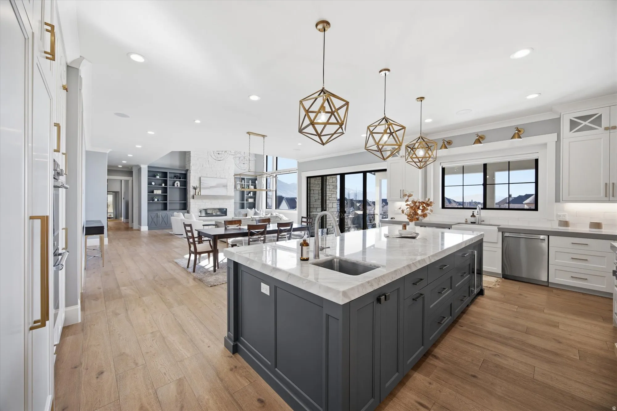 Two tone kitchen featuring dual tone cabinets, light stone countertops, a kitchen island with sink, light wood-style floors, and stainless steel dishwasher