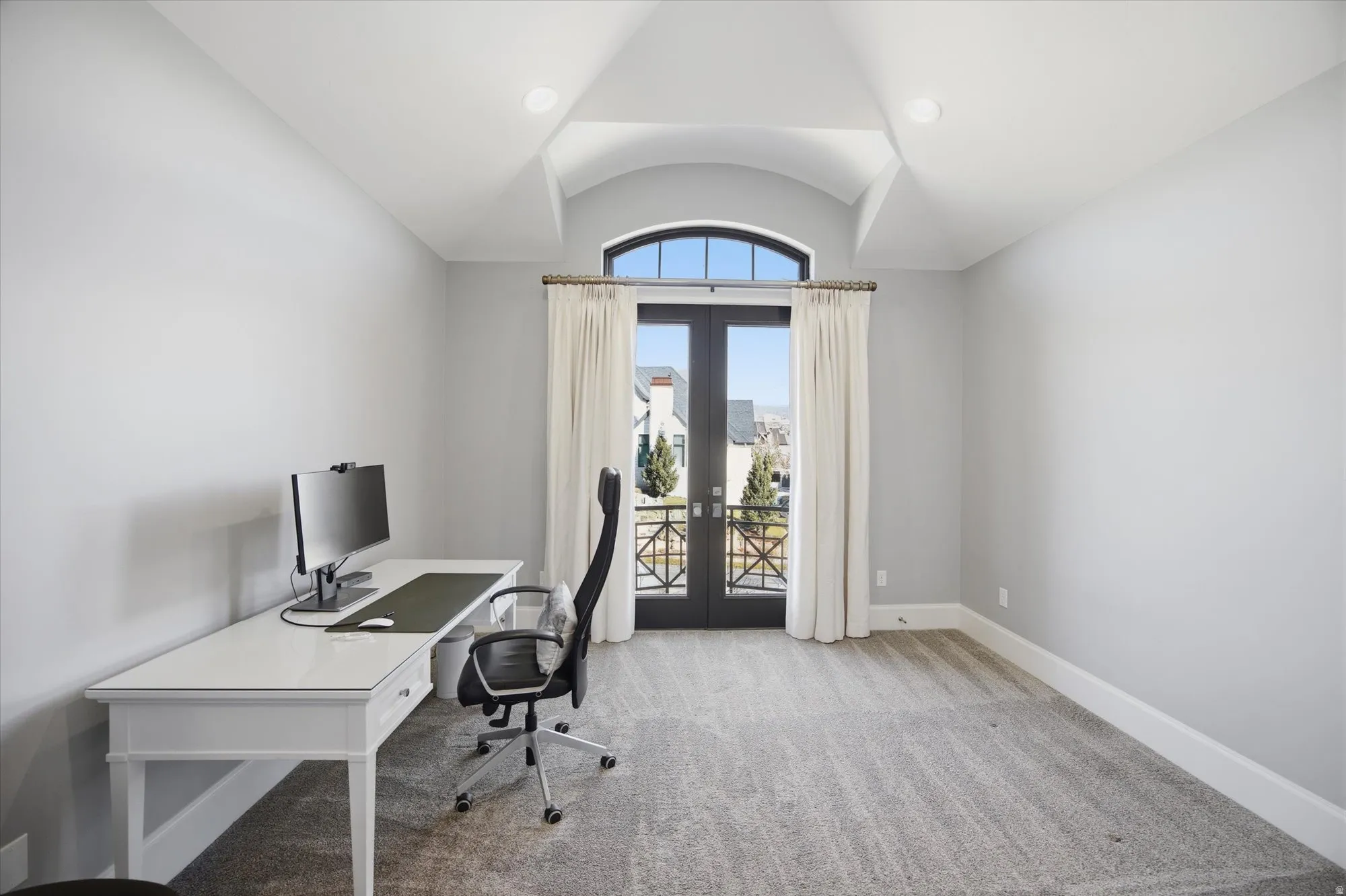 Office space featuring french doors, light colored carpet, and lofted ceiling