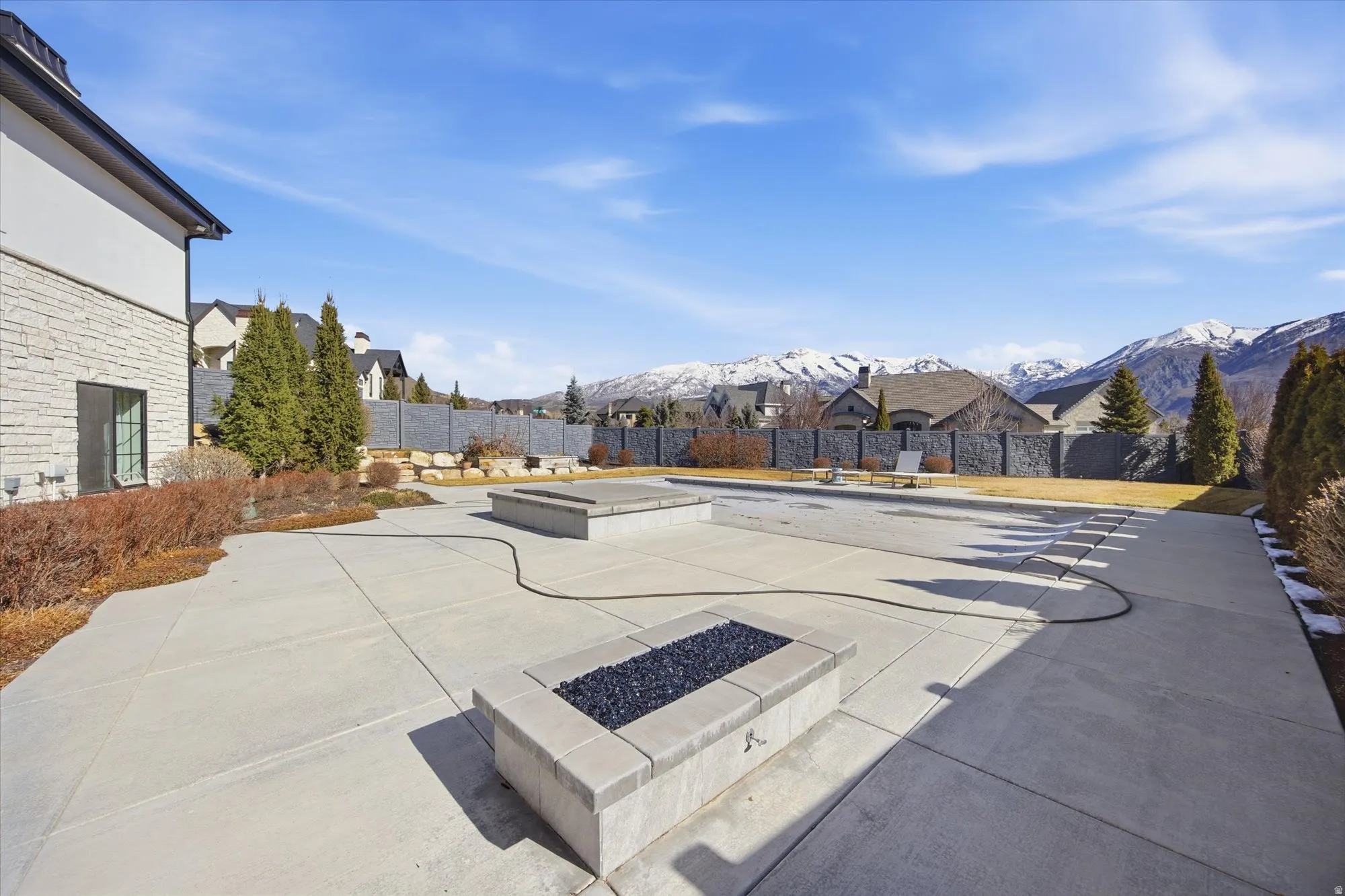 Fenced backyard featuring a fire pit, a mountain view, a patio area, and a residential view