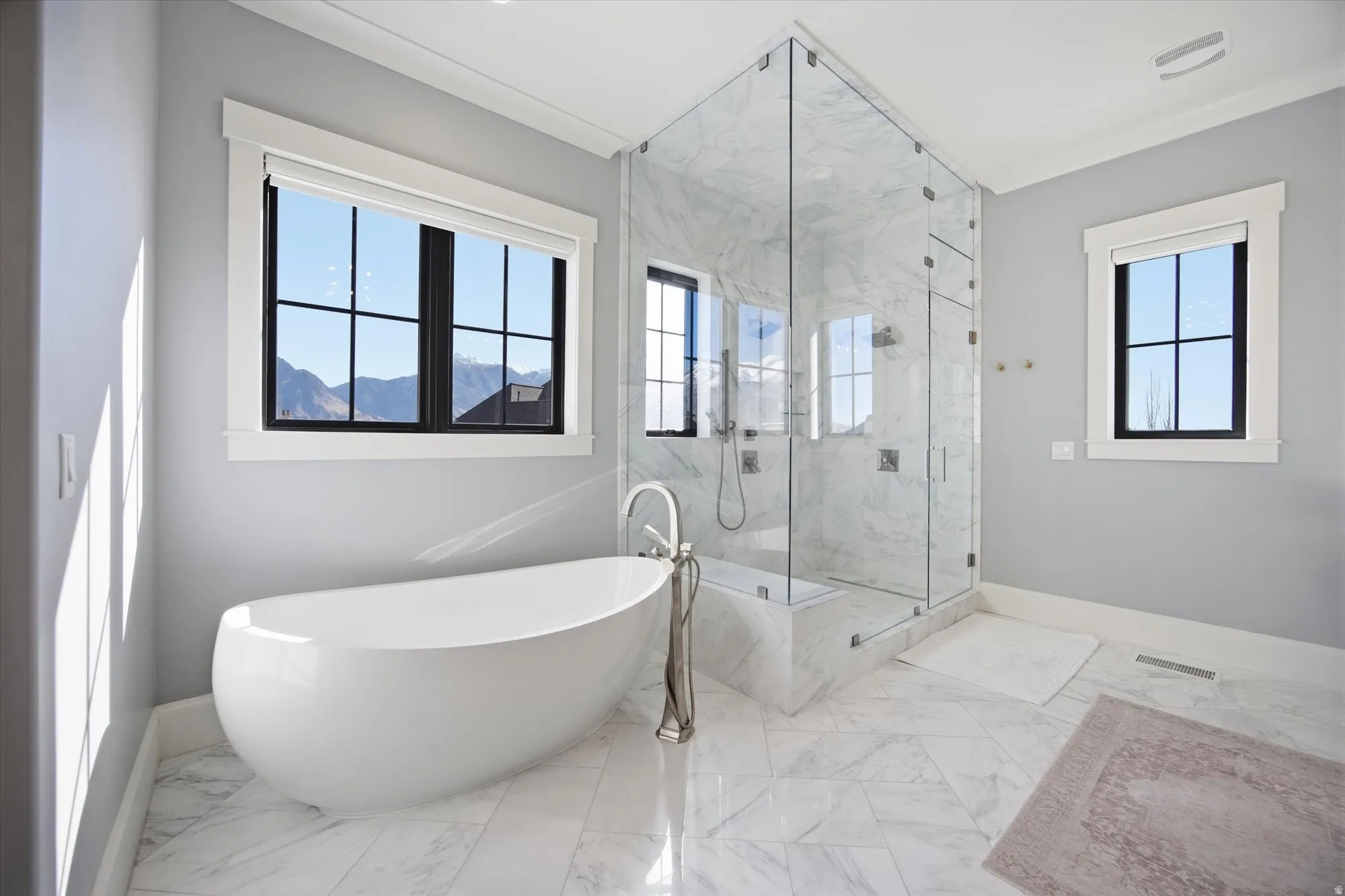 Bathroom with a marble finish shower, a freestanding bath, and light marble finish flooring