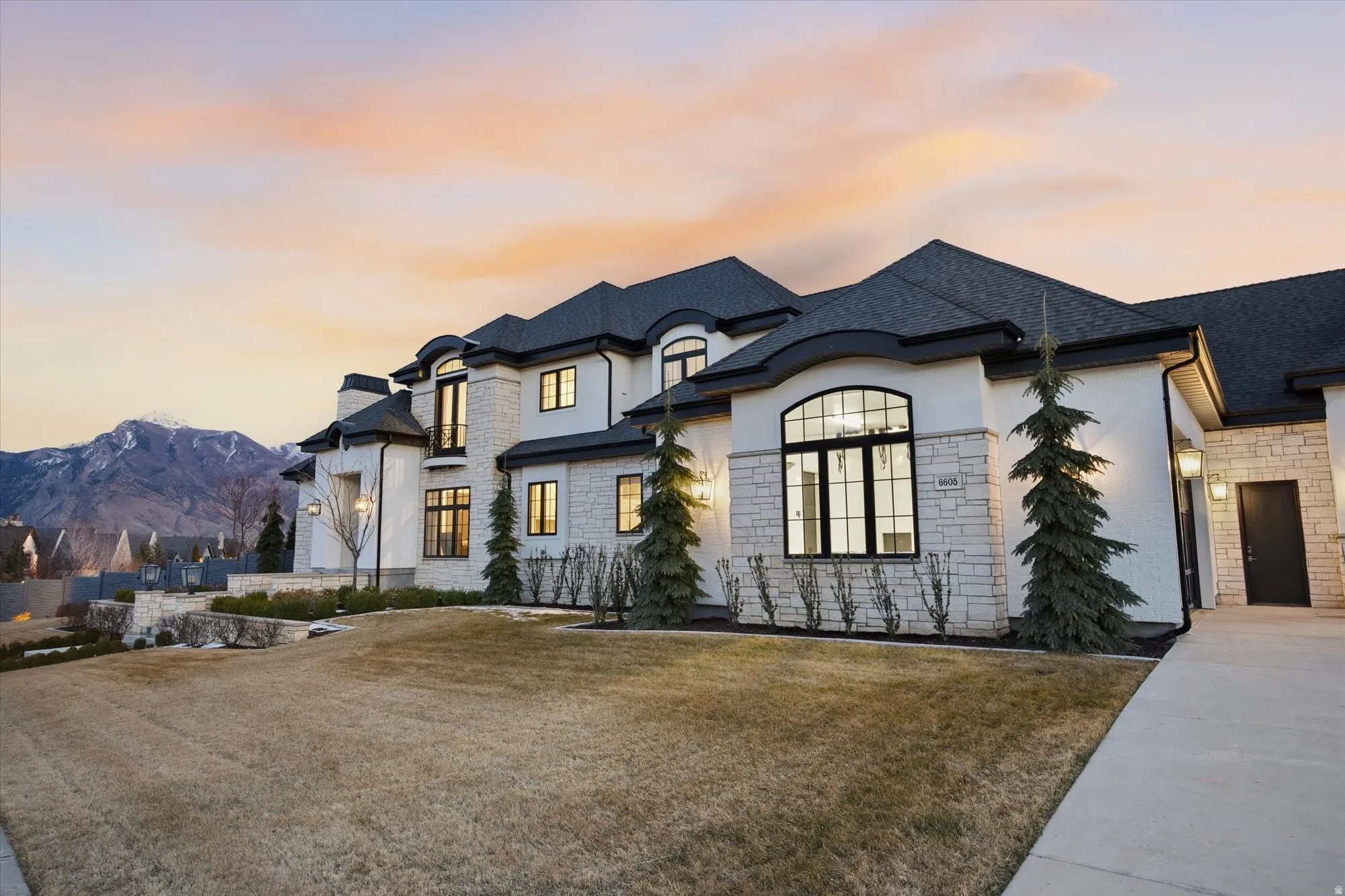 French country style house with stone siding, stucco siding, a front lawn, and a mountain view
