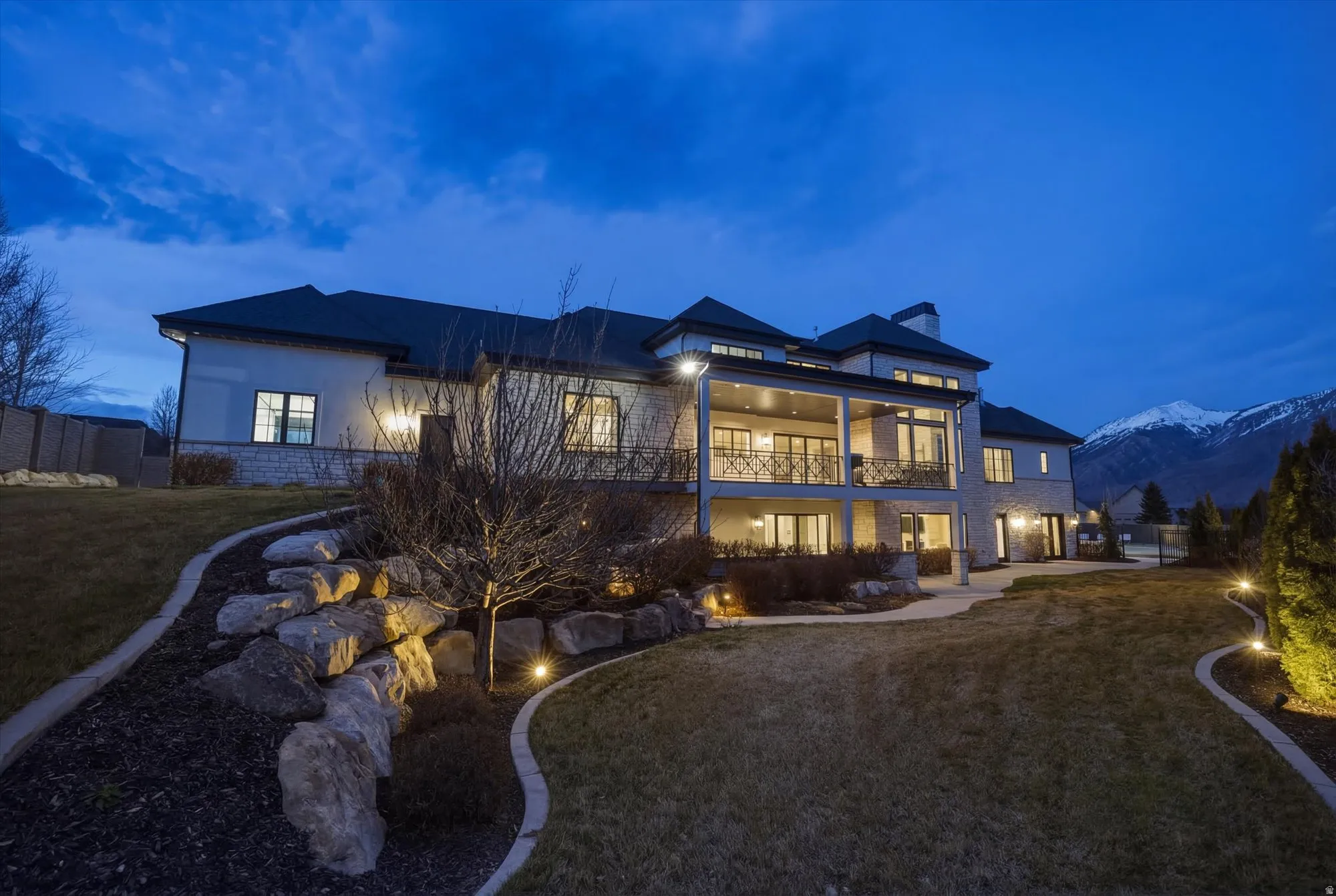 Back of property with a balcony, a patio, stucco siding, a chimney, and a mountain view