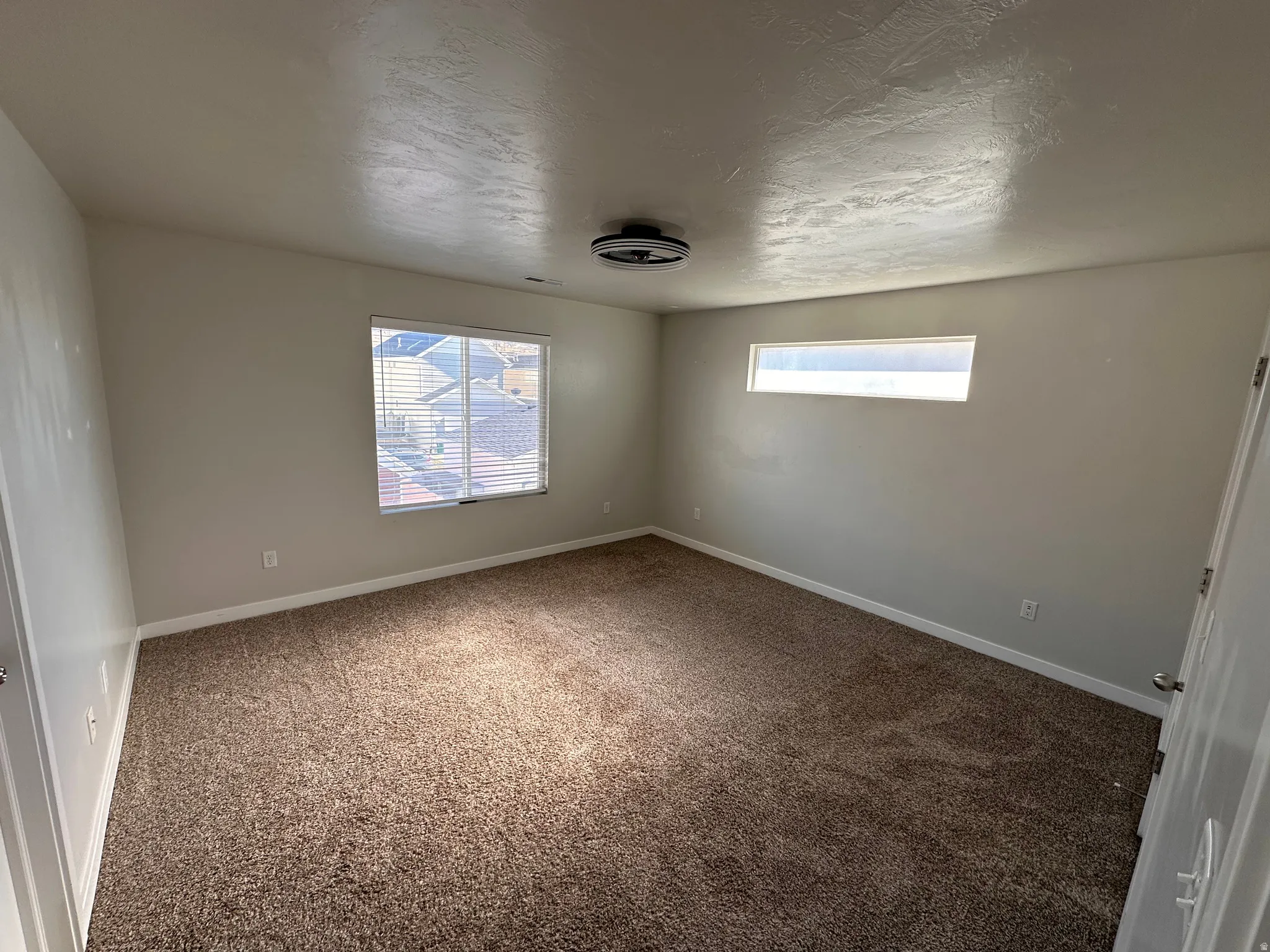 Empty room featuring dark carpet and a textured ceiling