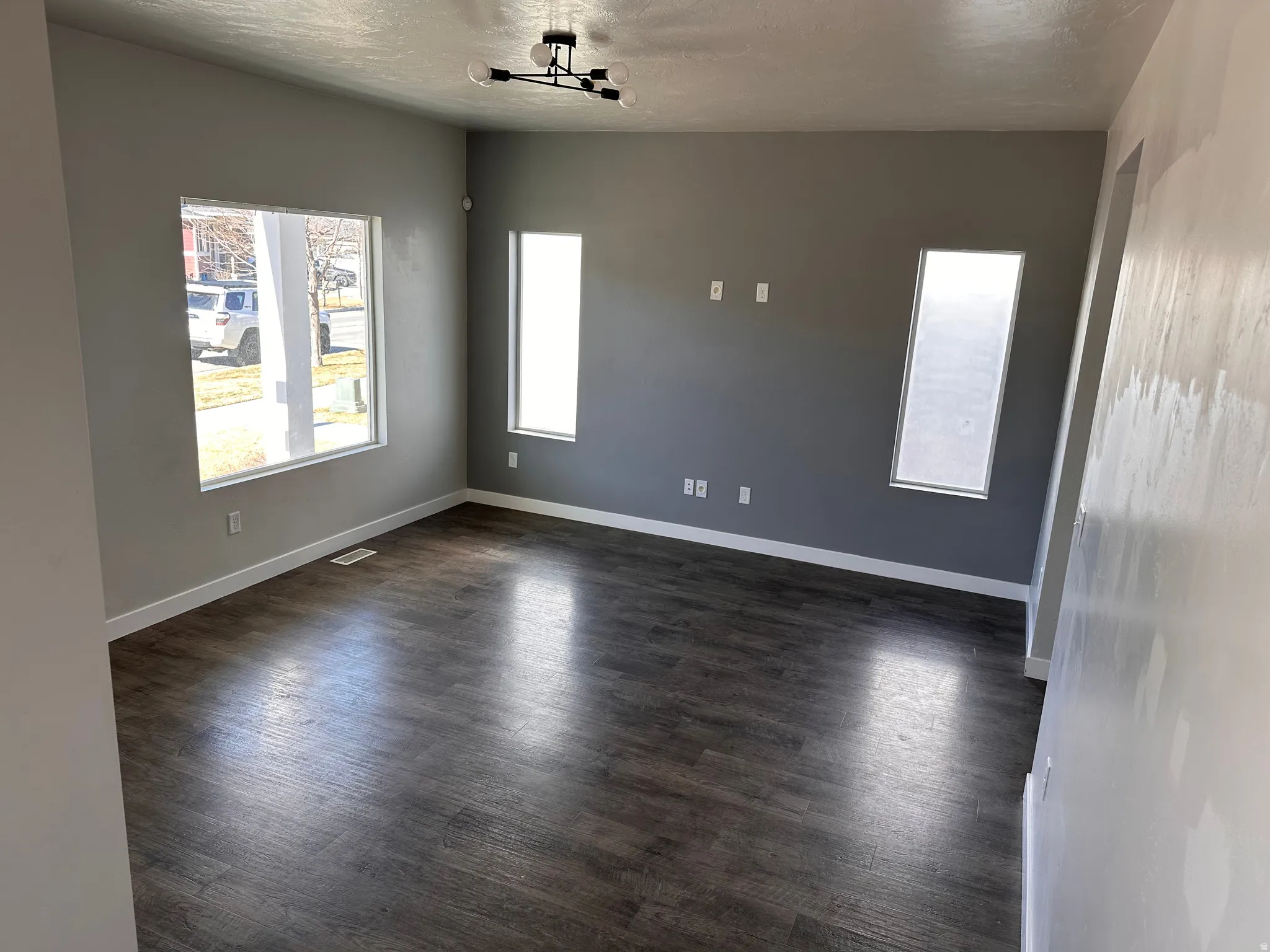 Empty room with dark wood-style flooring and a textured ceiling