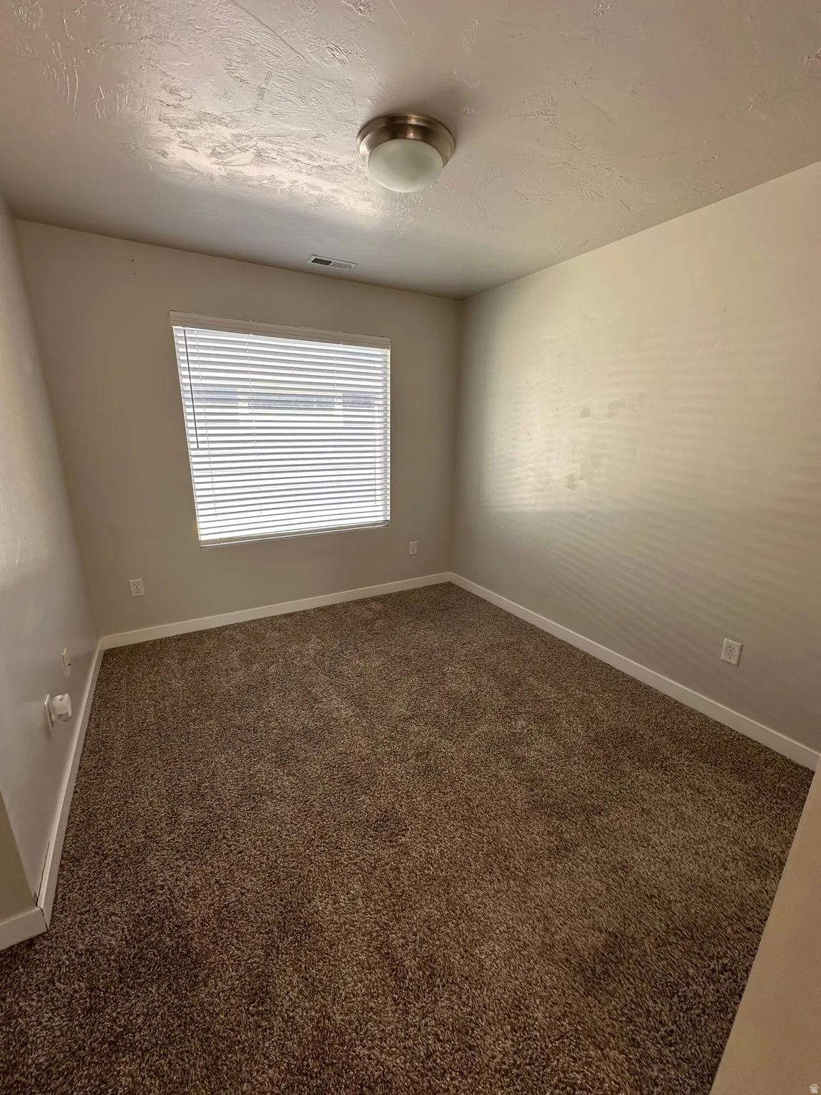 Spare room with dark carpet and a textured ceiling