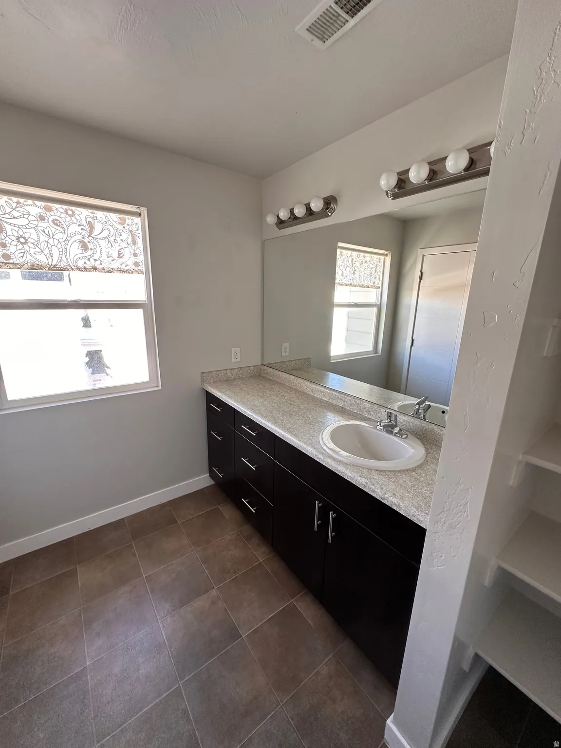 Bathroom featuring vanity and dark tile patterned floors