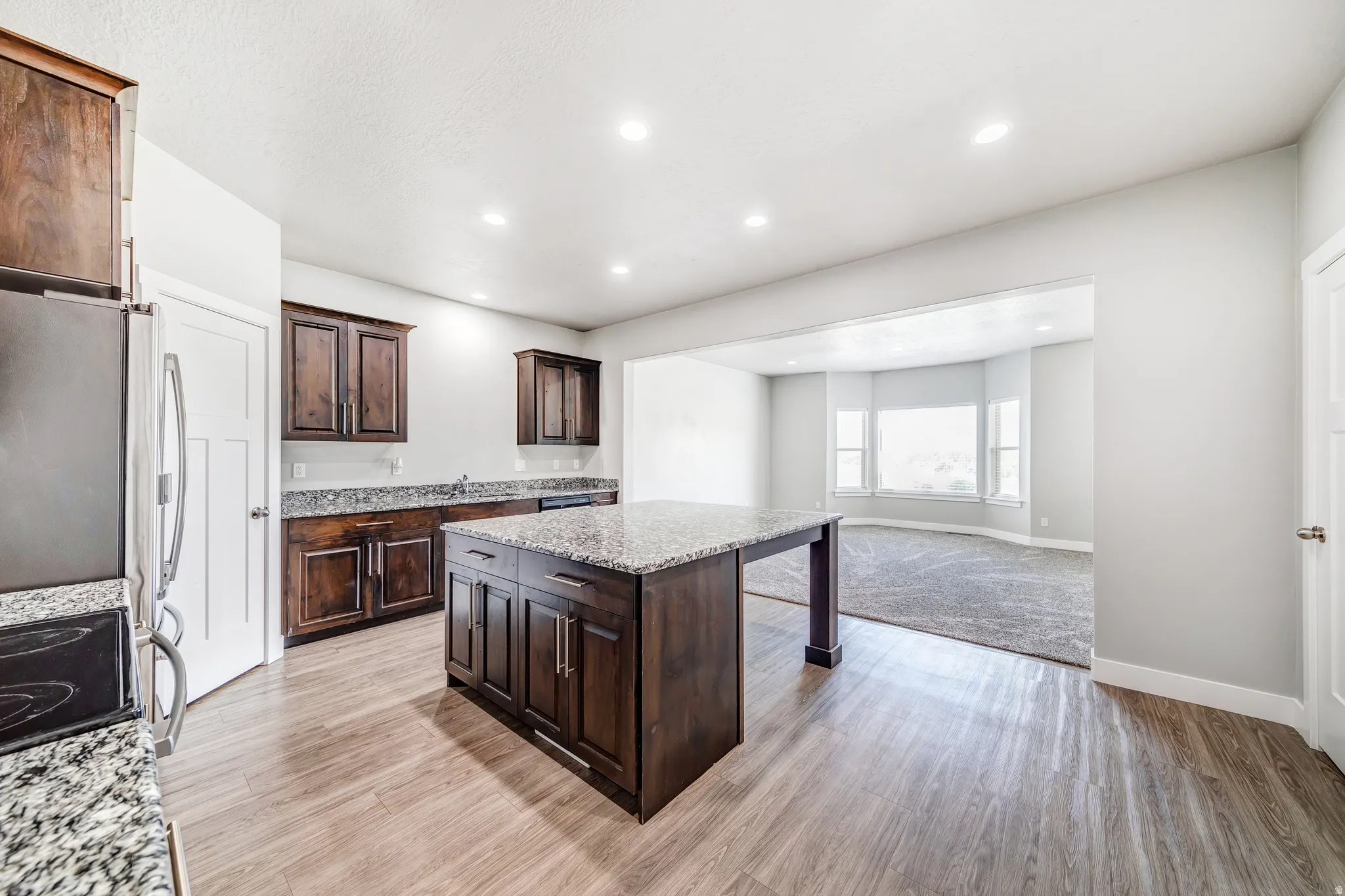 Kitchen featuring a kitchen bar, a center island, dark wood finish cabinets, light stone countertops, and light wood-type flooring