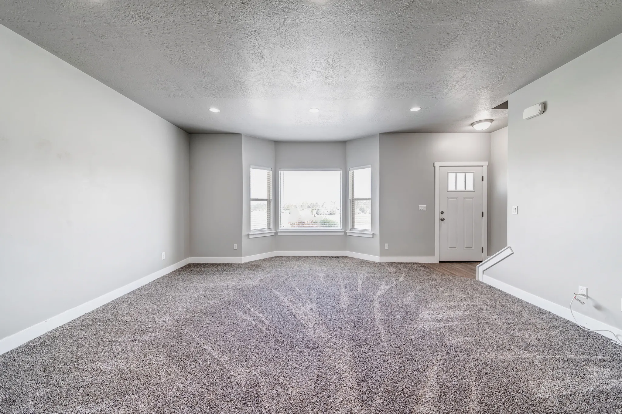Unfurnished living room featuring carpet, a textured ceiling, and recessed lighting