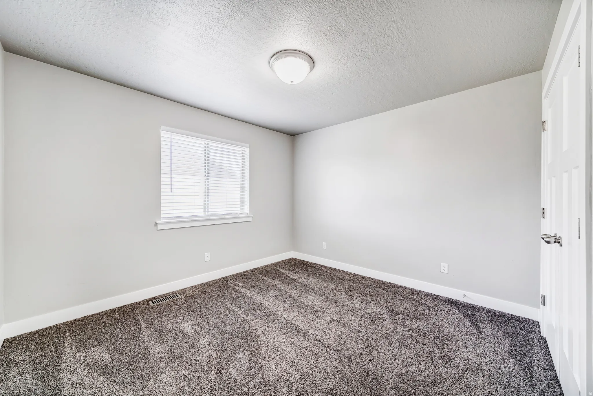 Empty room with dark colored carpet and a textured ceiling