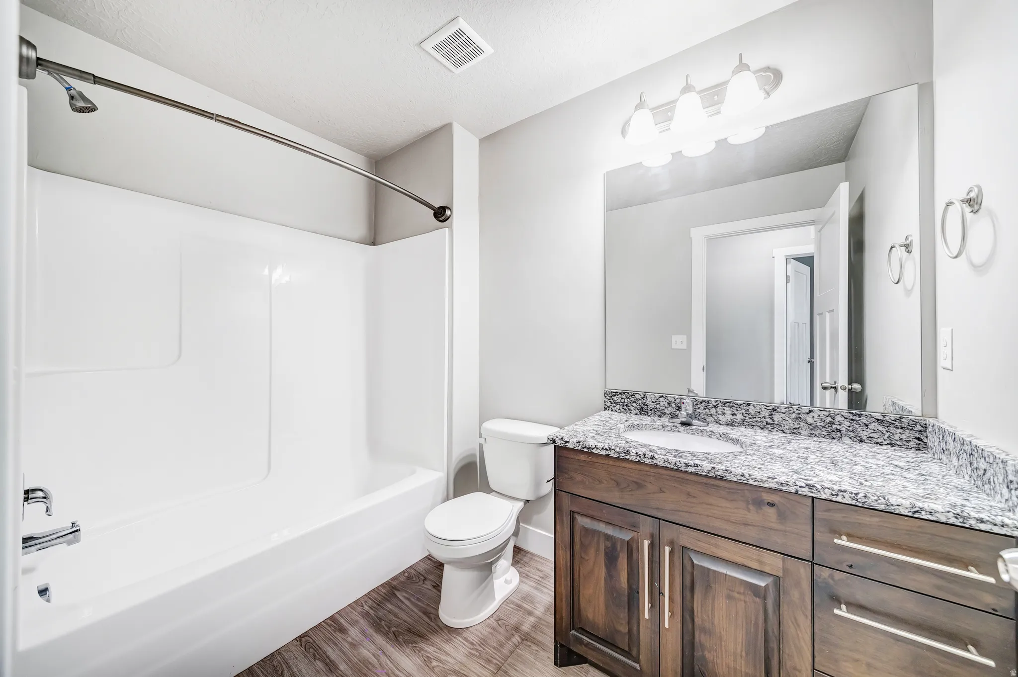Full bath with vanity, light wood-style floors, and shower / bath combination
