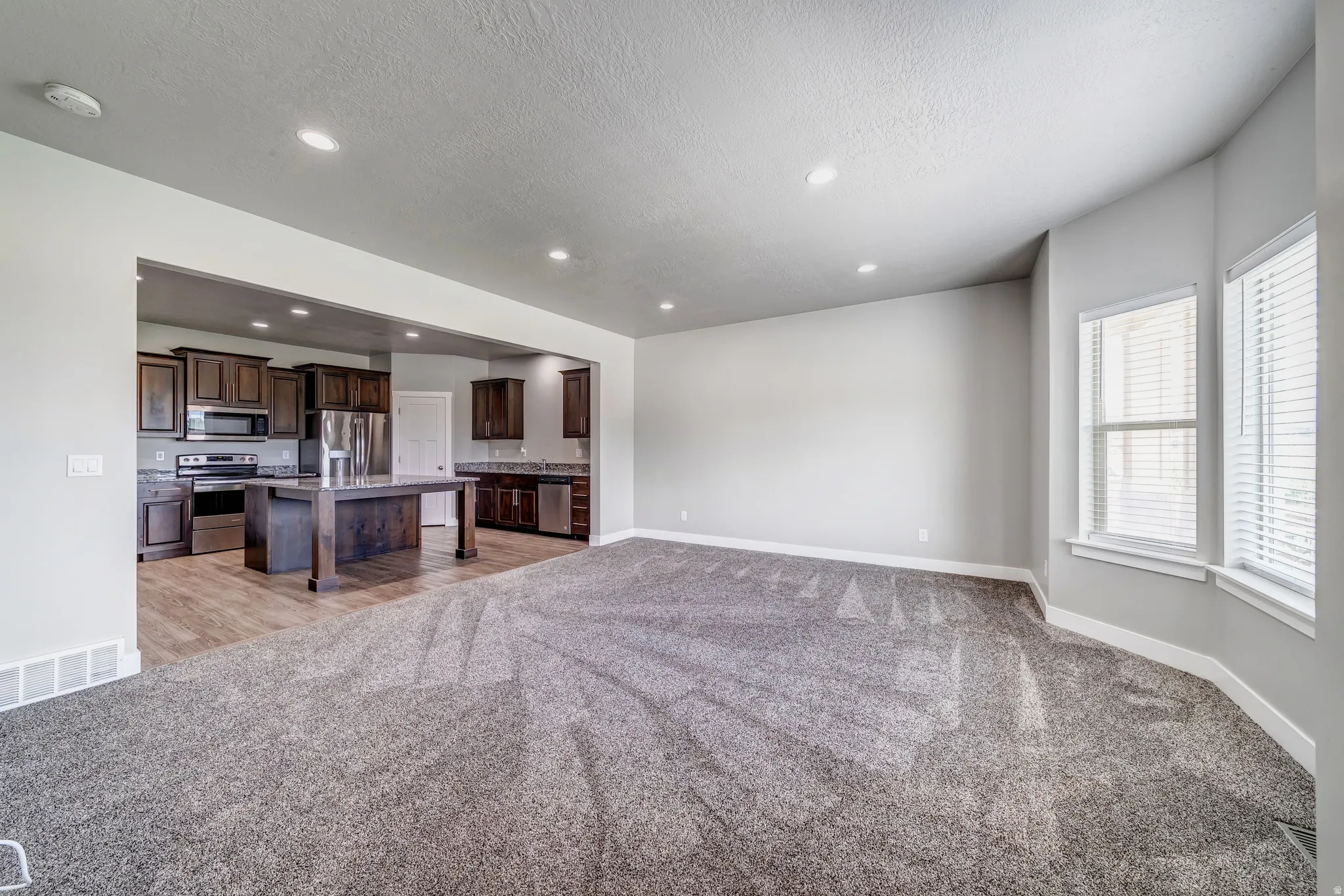Unfurnished living room with light carpet, recessed lighting, and a textured ceiling