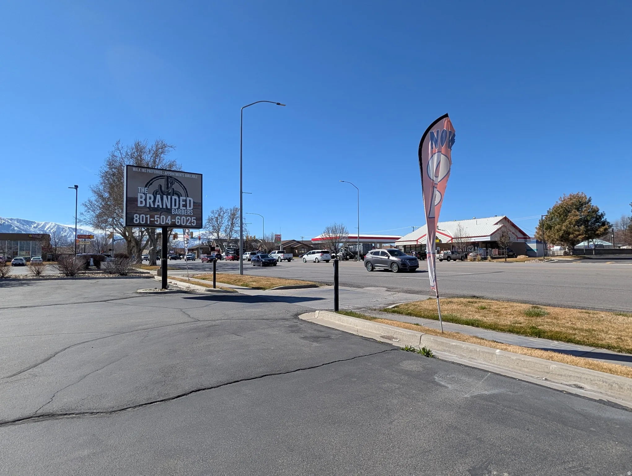 View of asphalt street featuring sidewalks, street lighting, and curbs