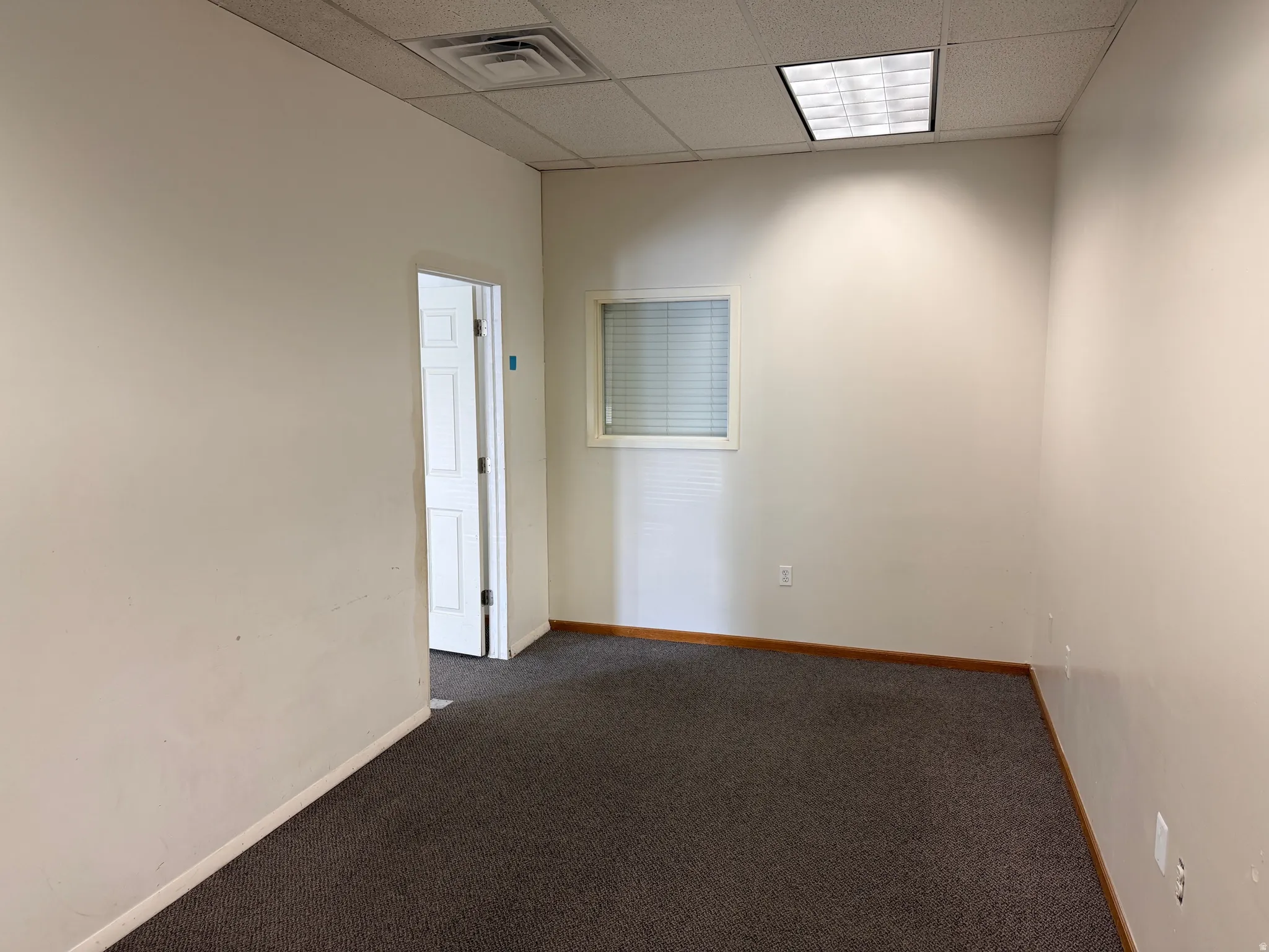 Empty room with a paneled ceiling and carpet floors