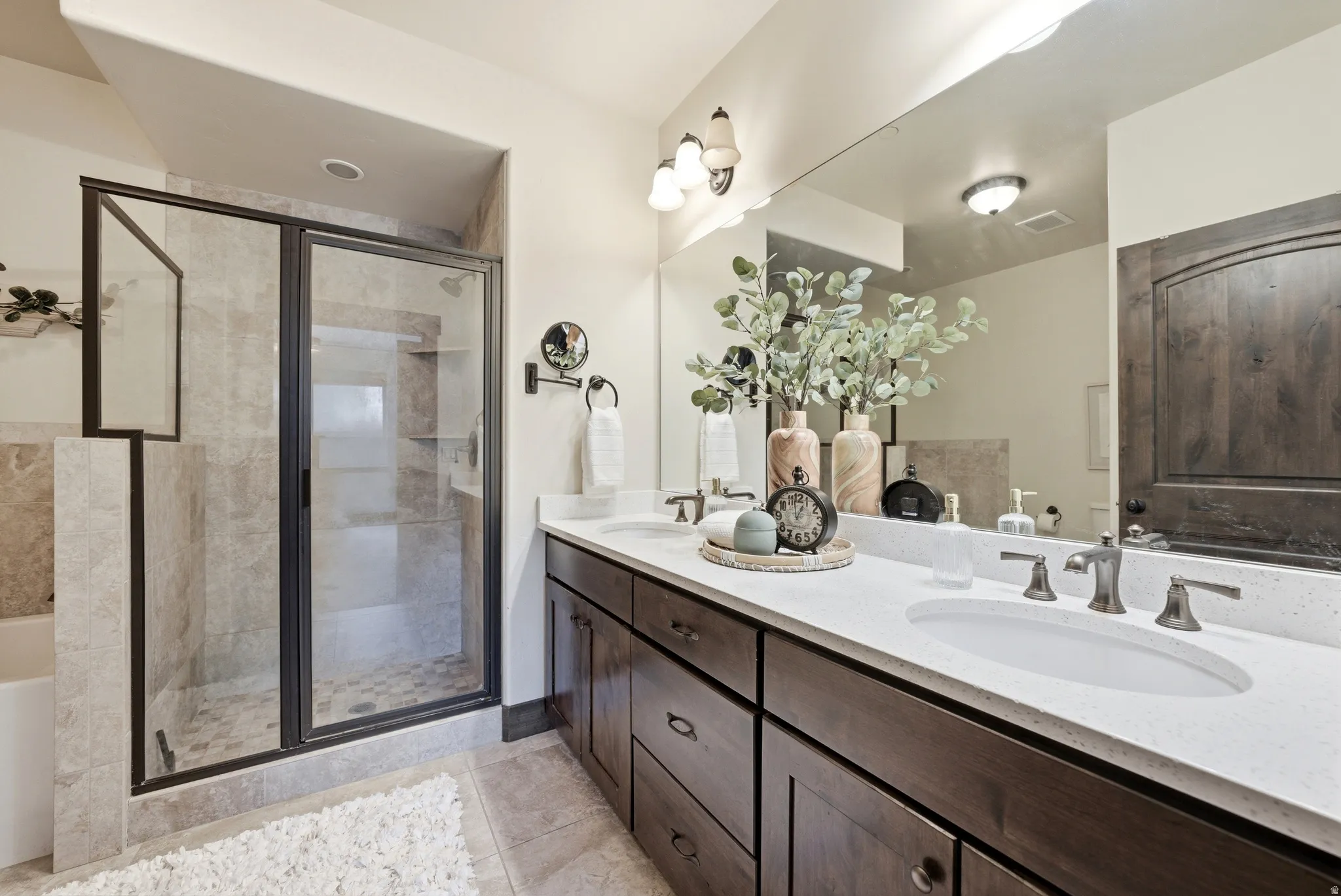 Full bath with a garden tub, double vanity, a shower stall, and light tile patterned floors