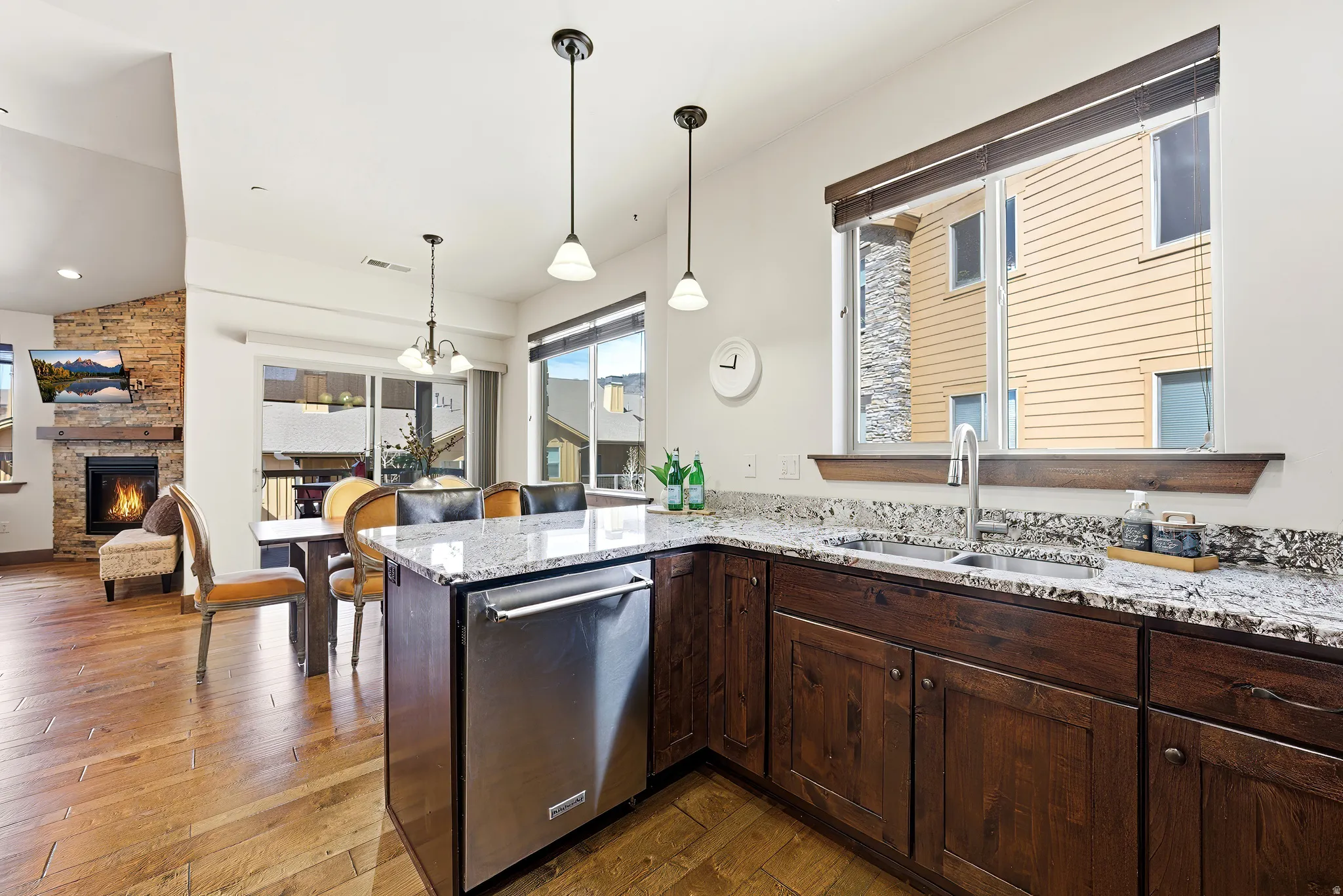 Kitchen featuring a peninsula, granite counters, stainless steel dishwasher, and  wood cabinets