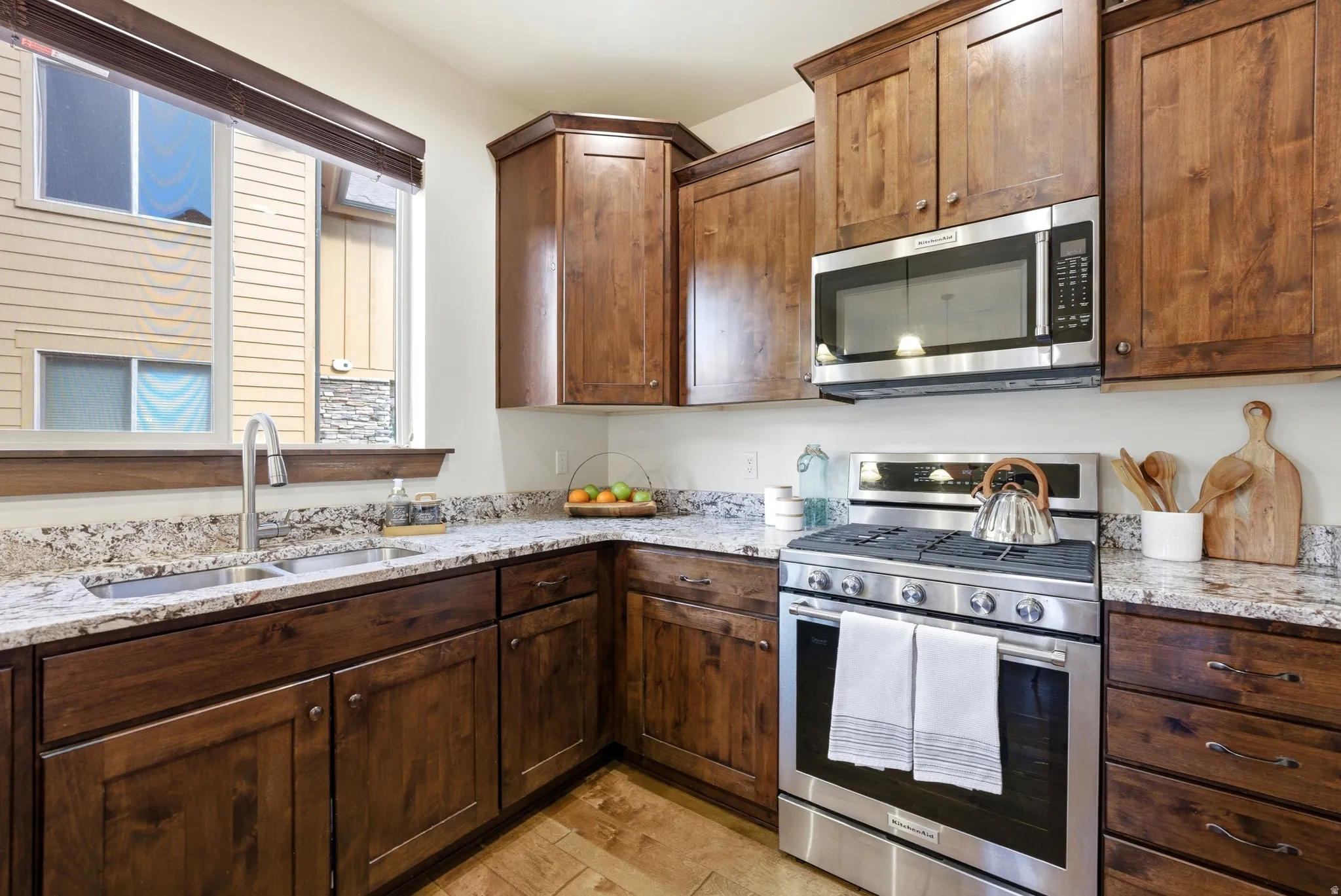 Kitchen featuring stainless steel appliances, light stone countertops, wood floors, and  wood