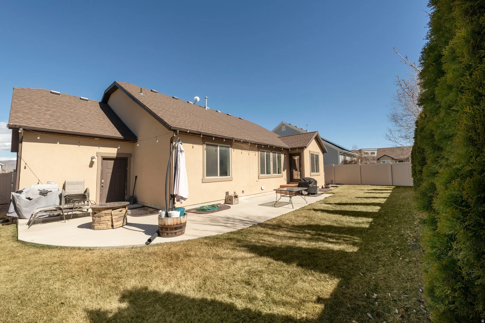 Rear view of property with a fenced backyard, a patio area, stucco siding, and roof with shingles