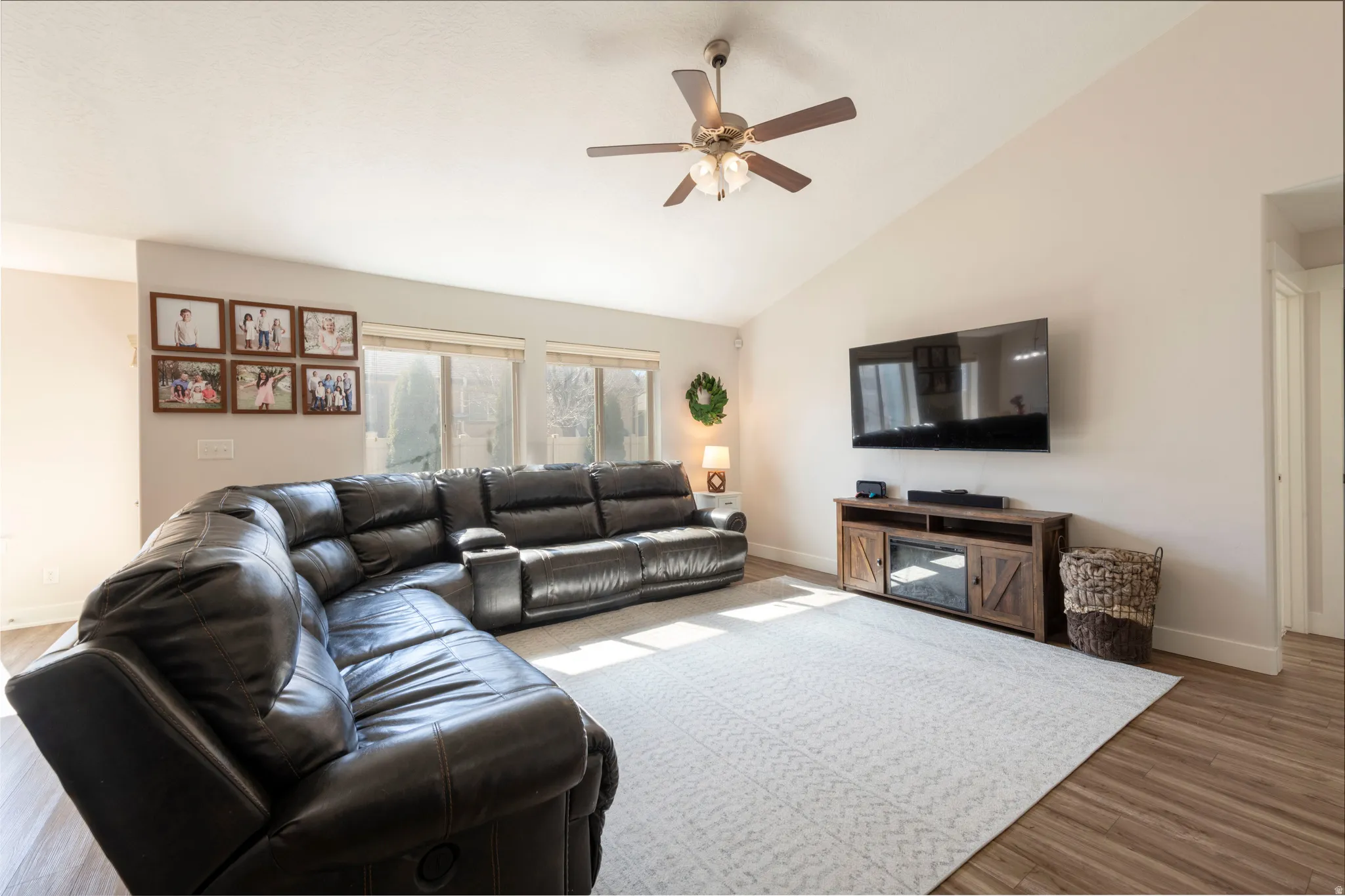 Living area featuring ceiling fan, light wood-style floors, and vaulted ceiling