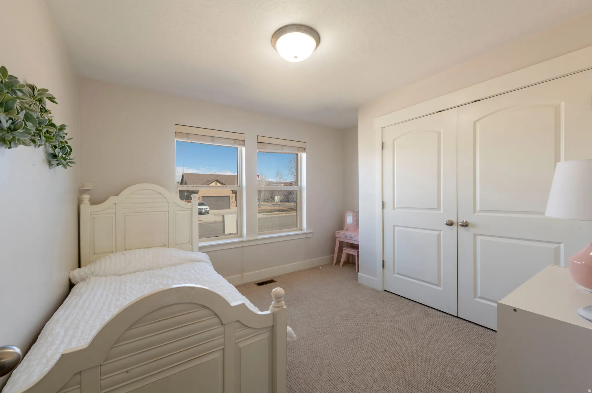 Bedroom with light colored carpet and a closet