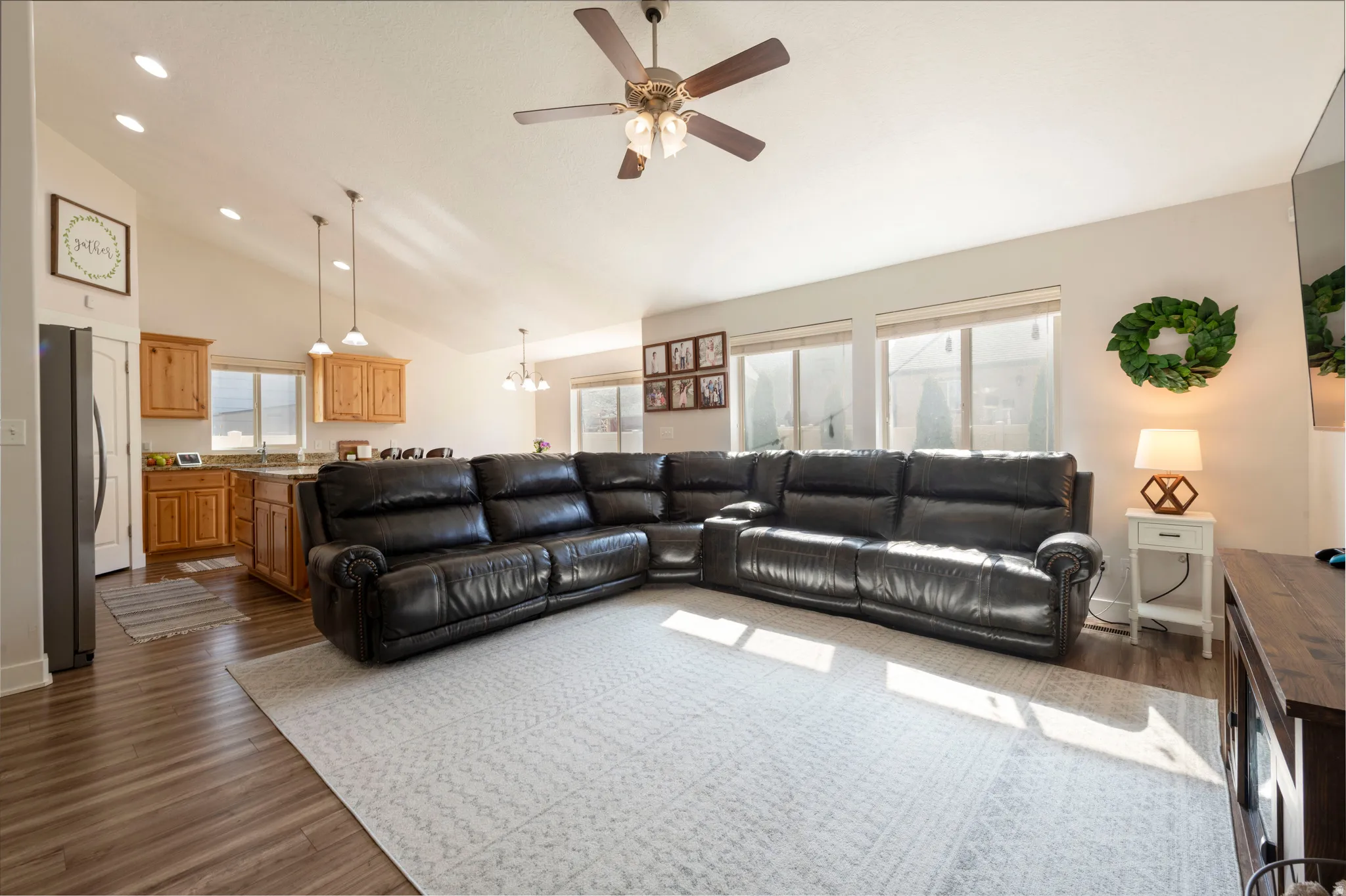 Living room featuring suspended lighting, dark wood-type flooring, a ceiling fan, and vaulted ceiling