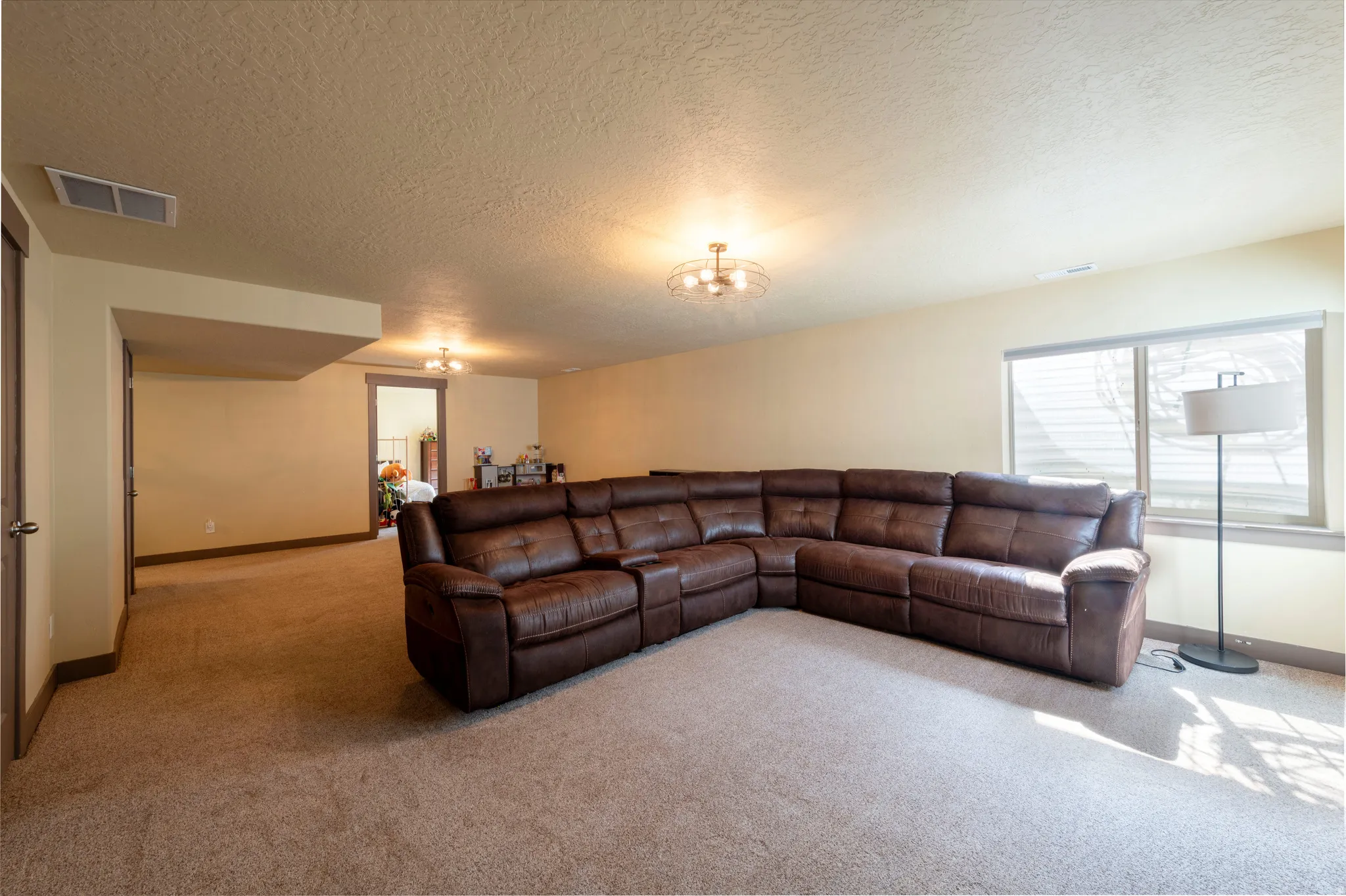 Carpeted living area featuring a textured ceiling and suspended lighting