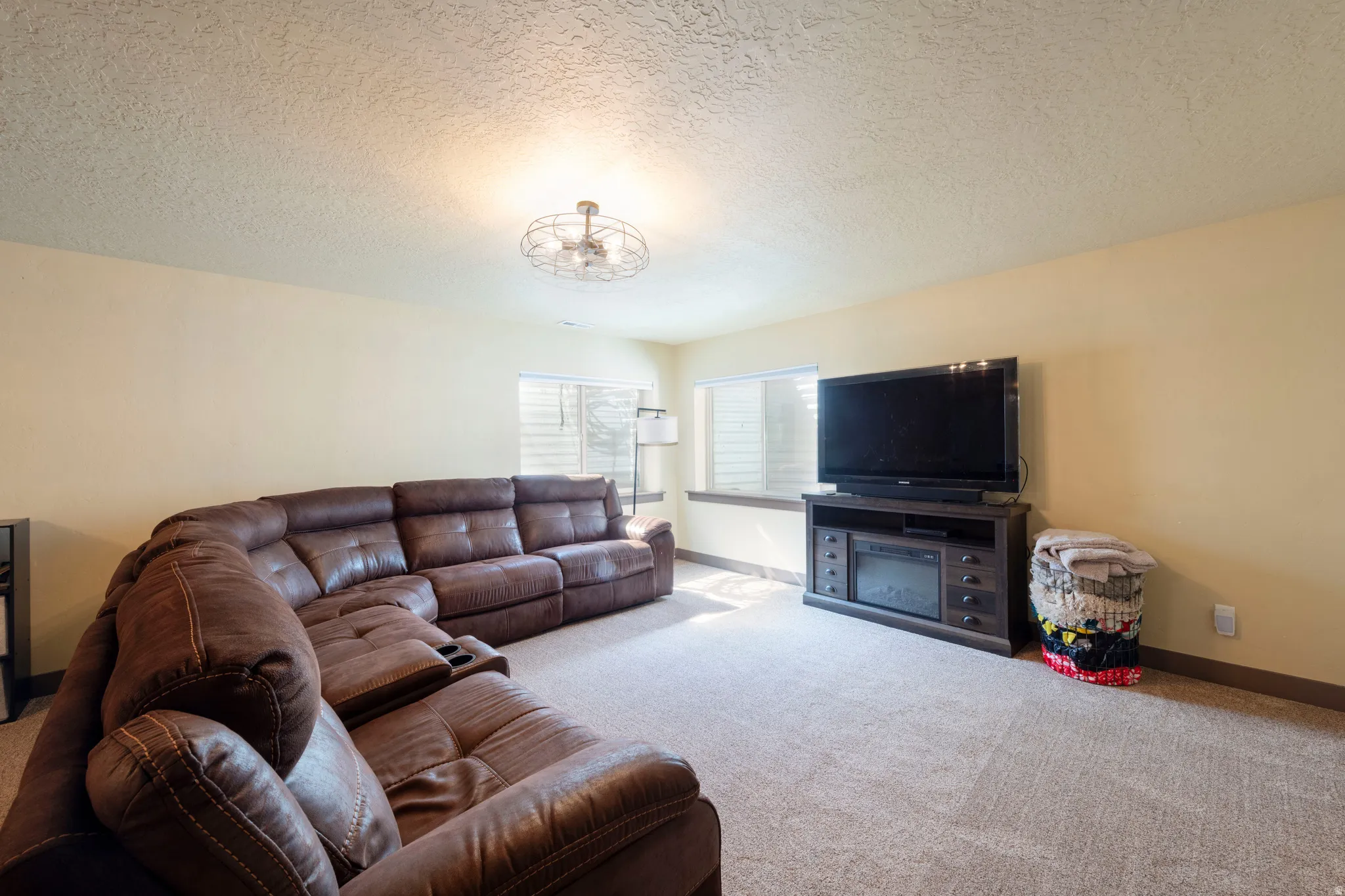 Carpeted living area featuring a textured ceiling and suspended lighting