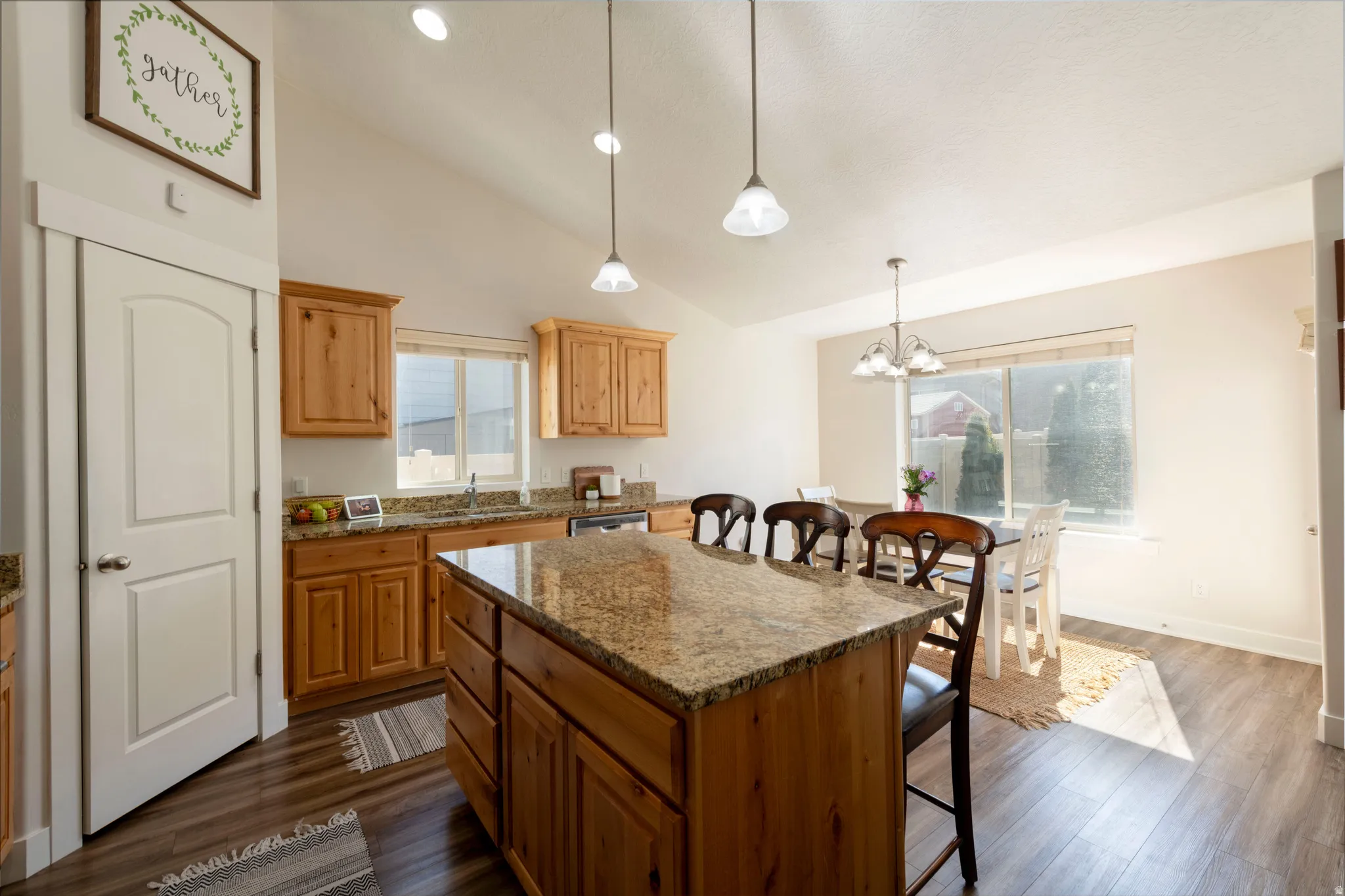 Kitchen featuring a kitchen bar, light stone countertops, a center island, lofted ceiling, and dark wood-type flooring