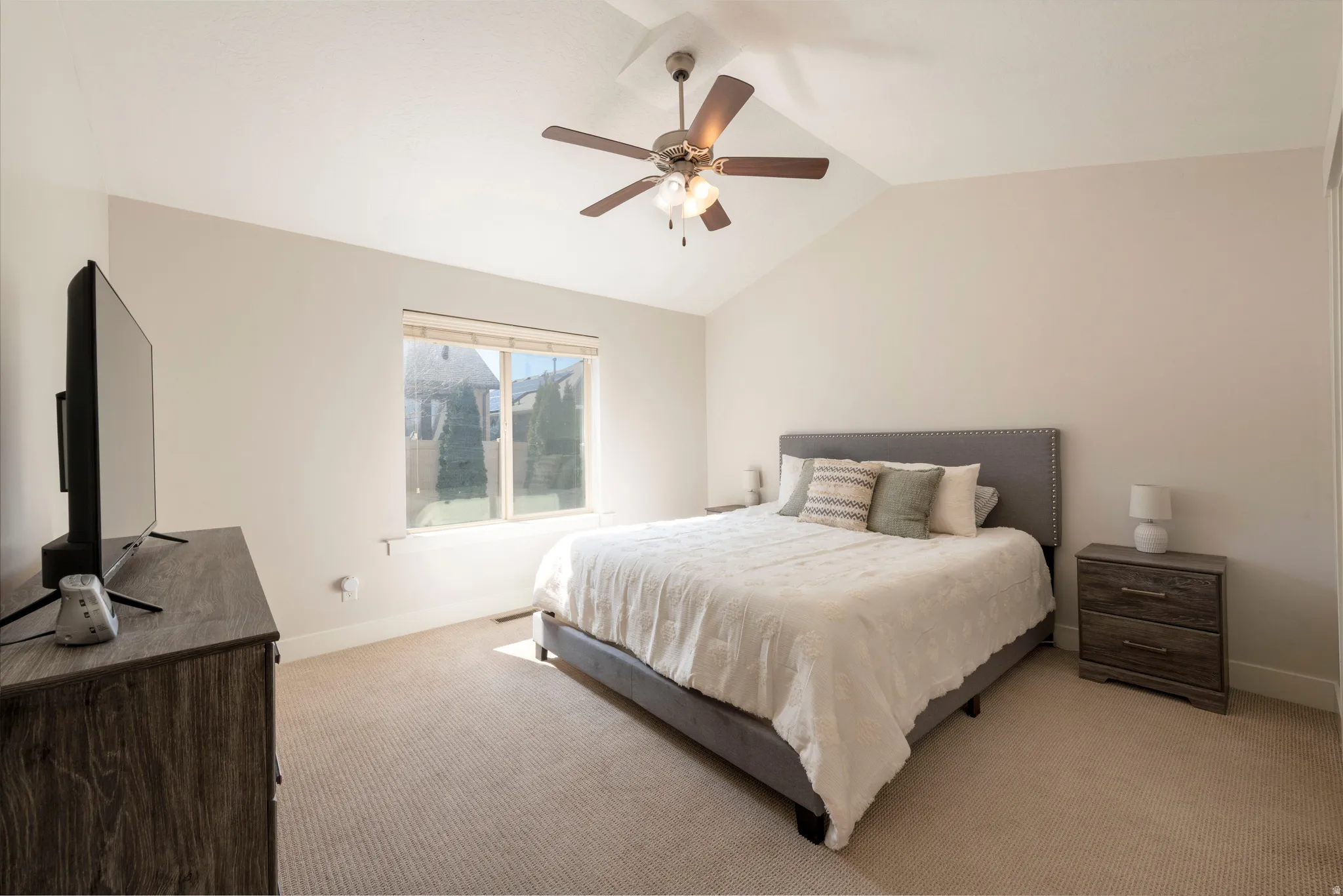 Carpeted bedroom with ceiling fan and vaulted ceiling