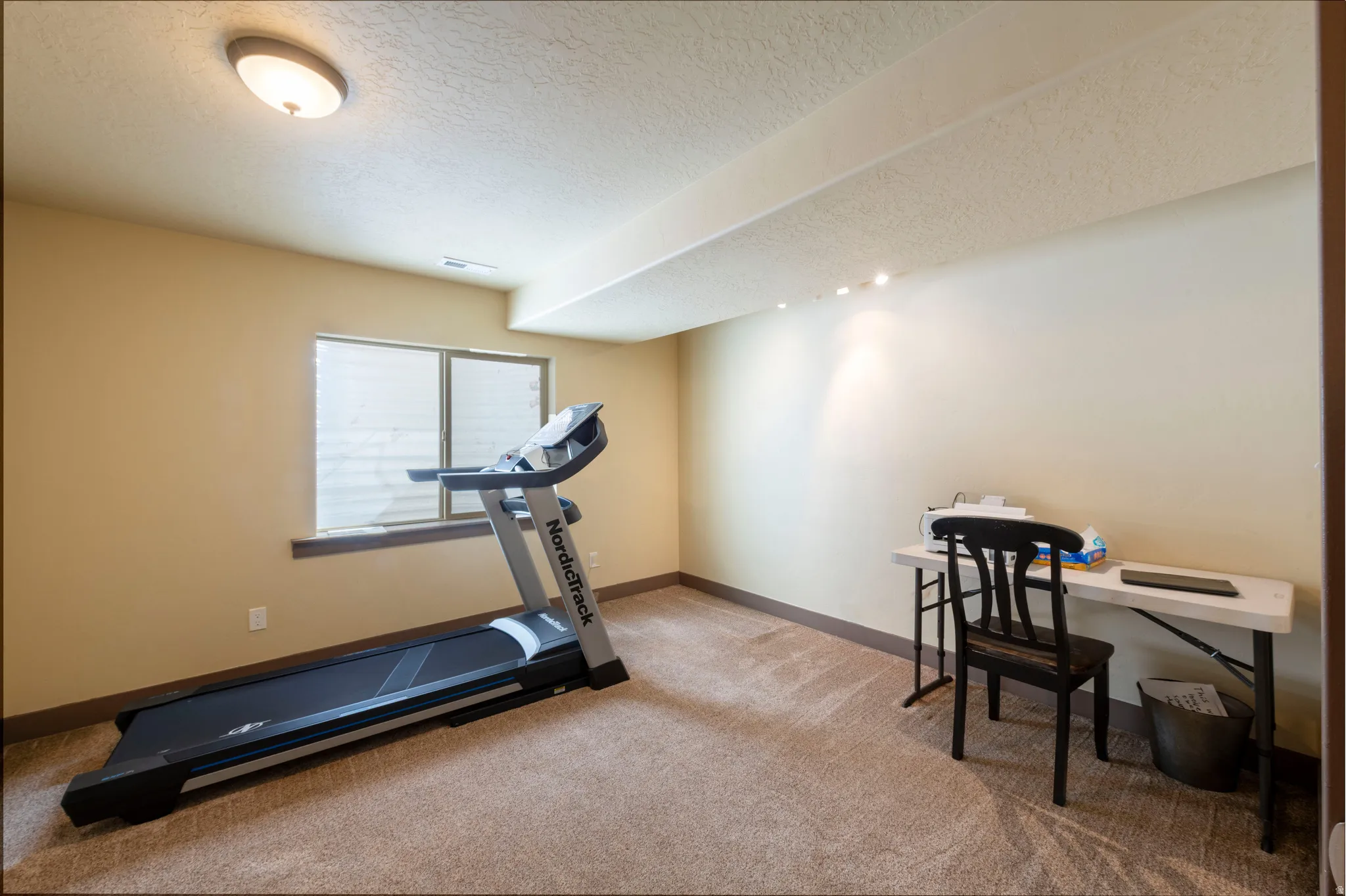 Workout room featuring light carpet and a textured ceiling