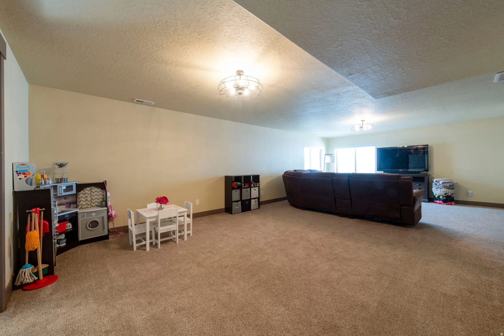 Playroom with a textured ceiling and light colored carpet
