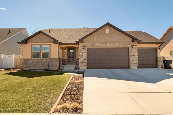 View of front of property with an attached garage, concrete driveway, stone siding, and a shingled roof