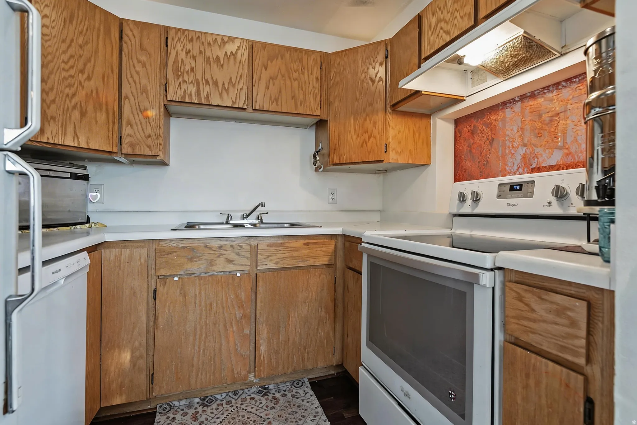 Kitchen with white appliances, light countertops, and wood finish cabinetry