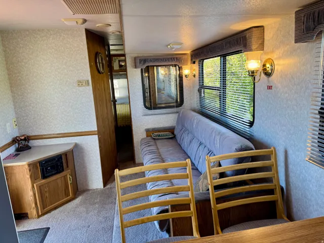 Interior featuring a built-in sofa, dual windows with blinds, and wall-mounted sconces