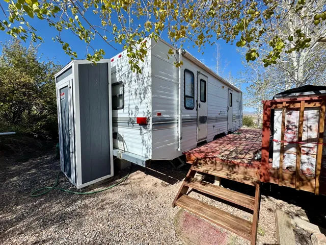 Mobile home exterior featuring white siding, multiple windows, and a wood-finish deck with steps