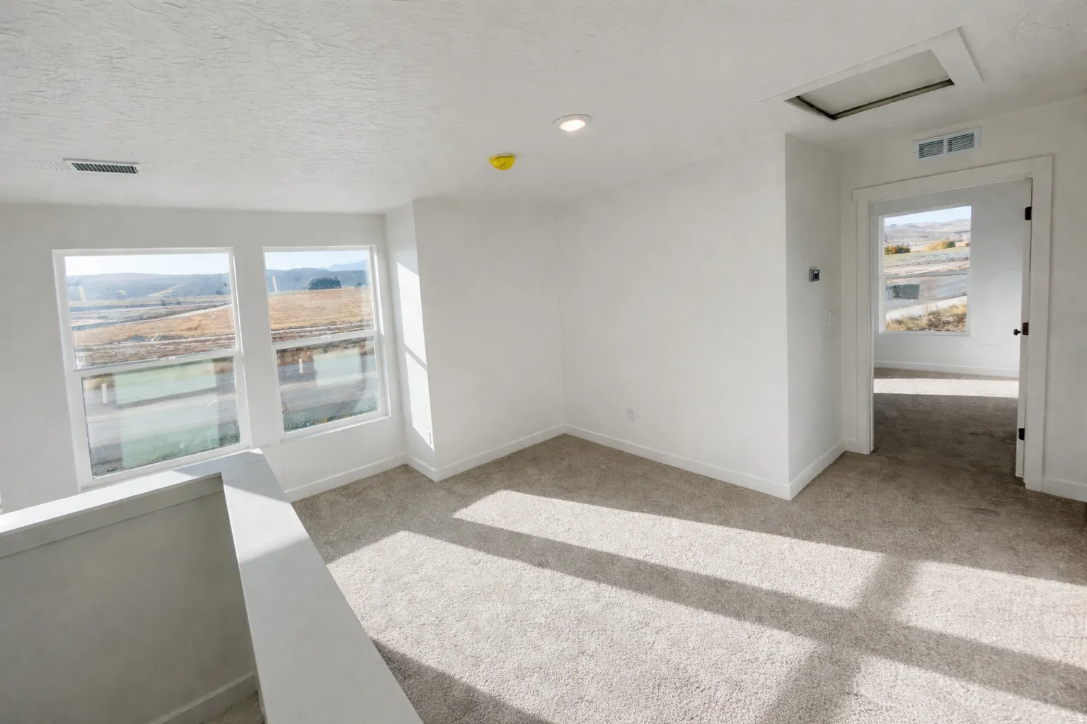Unfurnished room featuring healthy amount of natural light, light colored carpet, and a textured ceiling