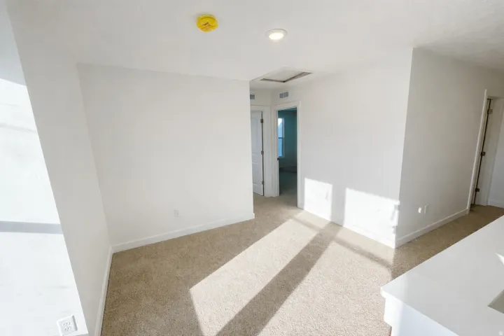 Spare room with light colored carpet and a smoke detector