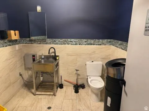 Half bathroom with toilet and tile walls