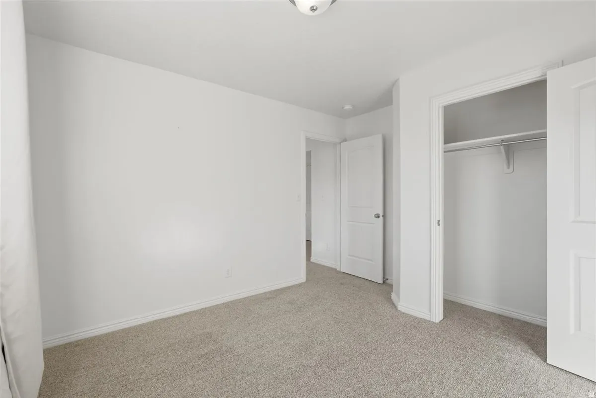 Unfurnished bedroom featuring light carpet and a closet