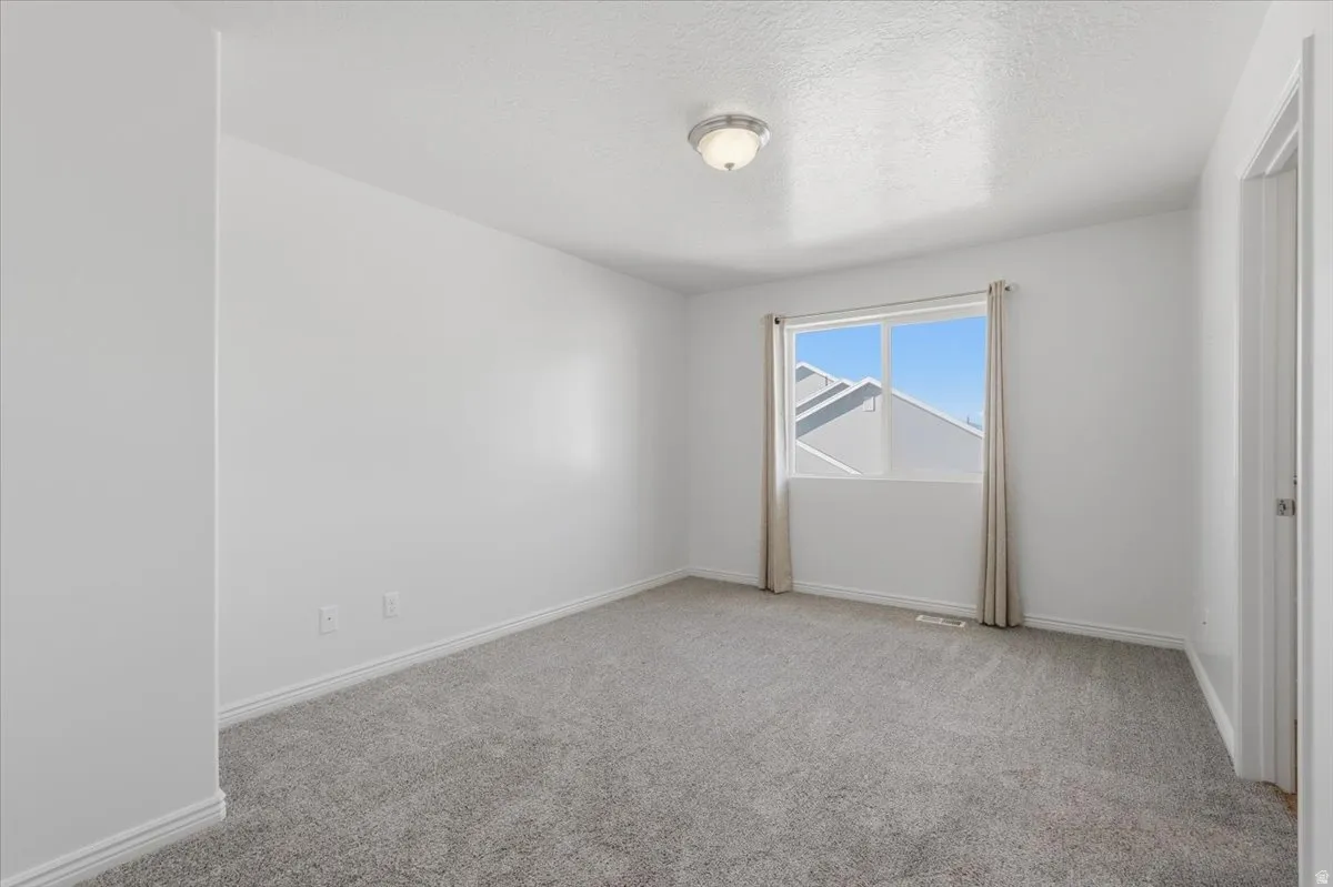 Unfurnished room with light colored carpet and a textured ceiling