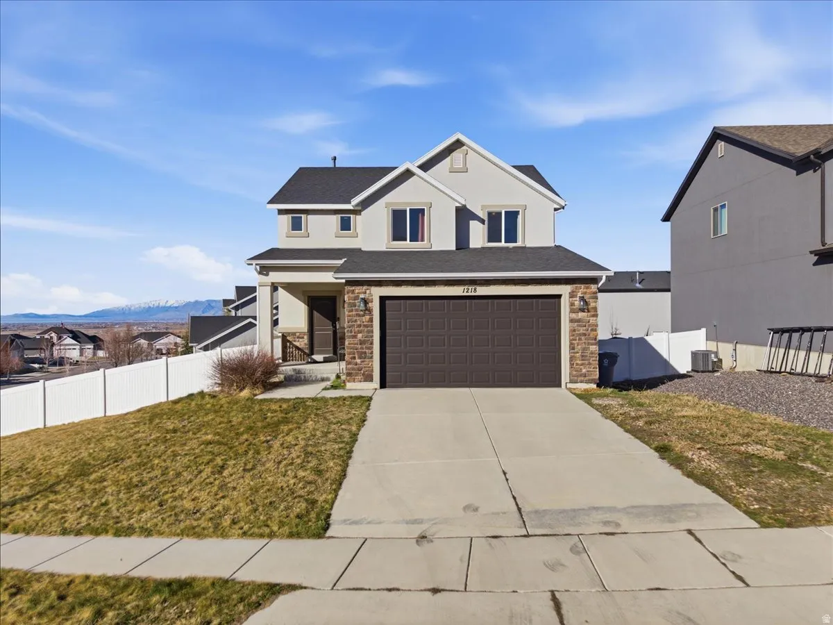 Traditional-style home featuring a porch, concrete driveway, an attached garage, and stone siding
