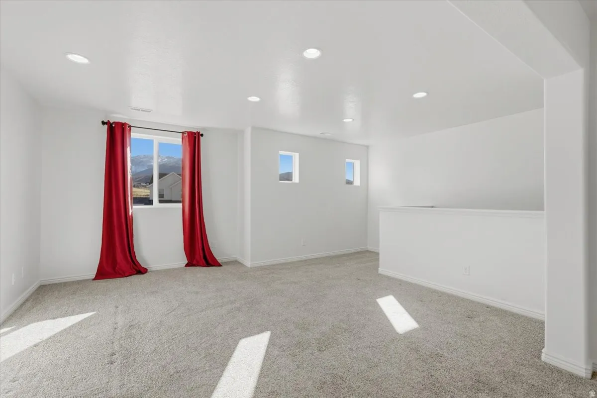 Empty room with light carpet and recessed lighting