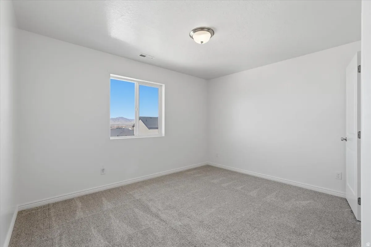 Unfurnished room featuring light carpet and baseboards