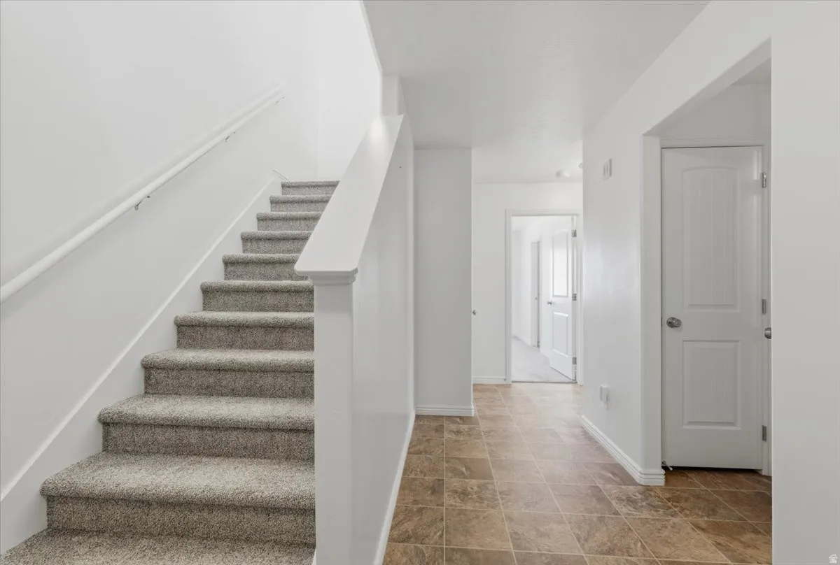 Staircase with baseboards and stone finish floors