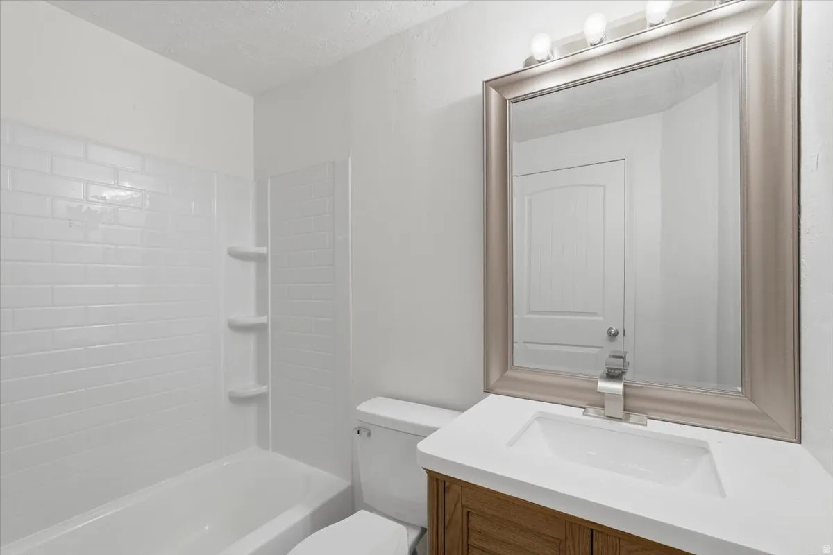 Full bath with vanity, bathing tub / shower combination, and a textured ceiling